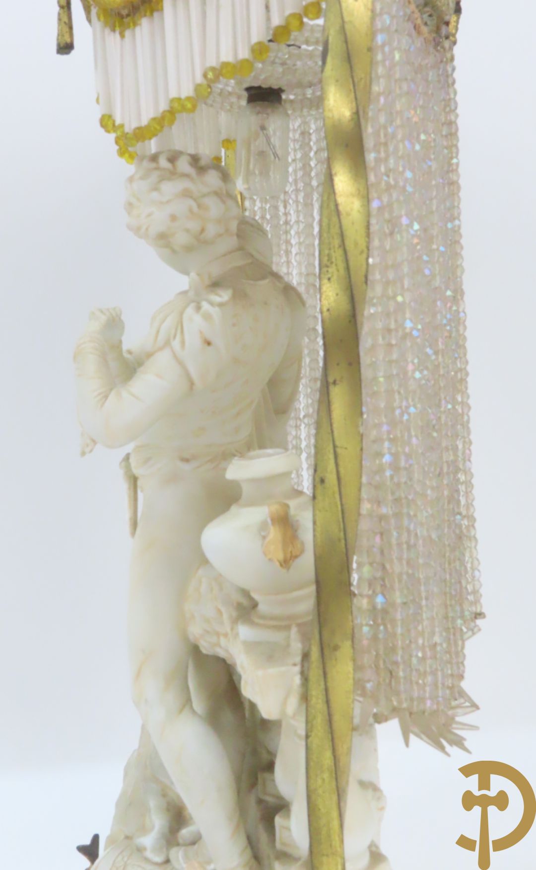 Lieftallig biscuit van romantisch koppel bij amfoor met kleine neergezeten cupido onder koperen baldakijn met kristallen belletjes