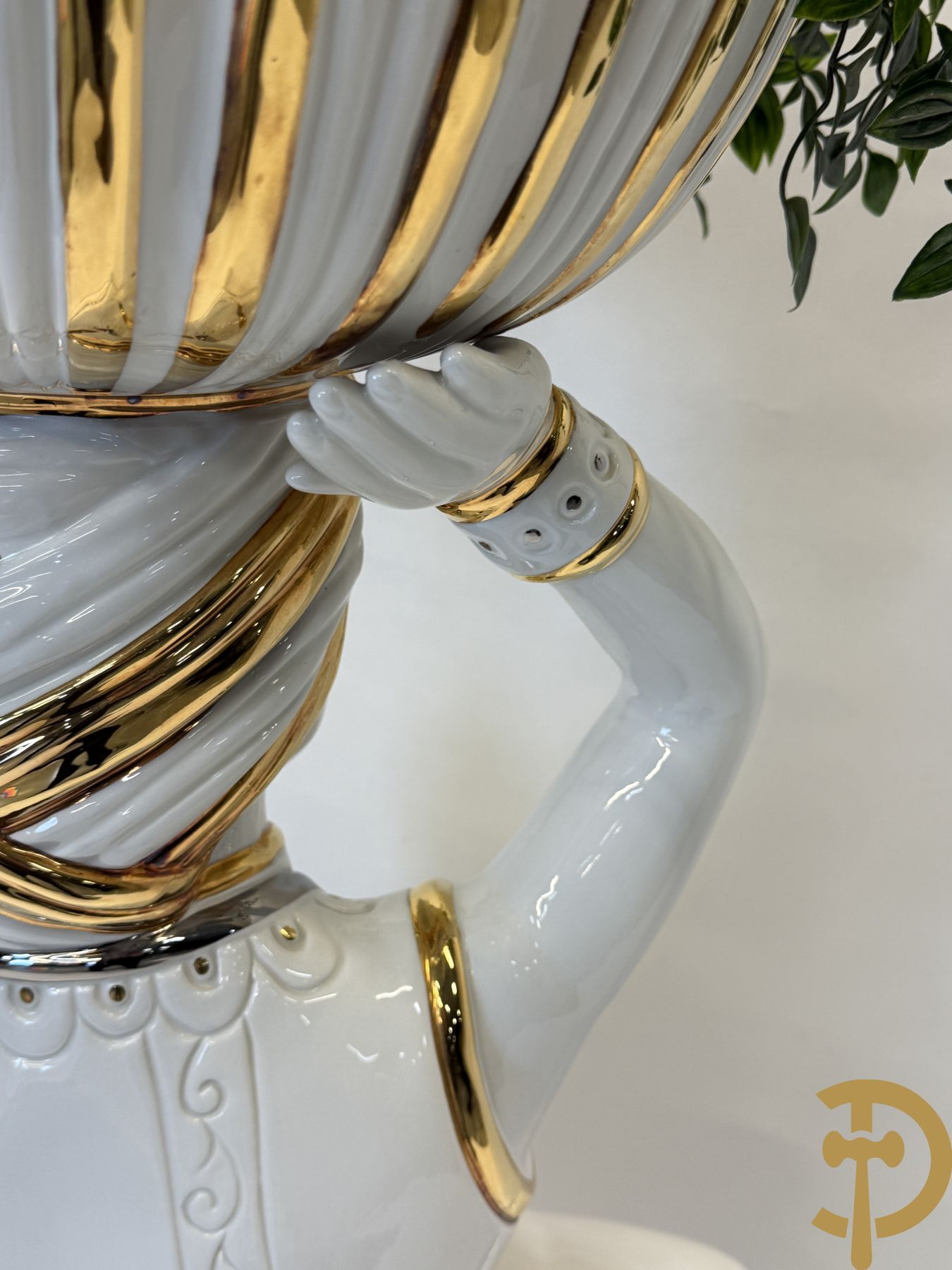 Porseleinen sierbeeld van olifant als staander met daarboven jongeman met bloemencachepot