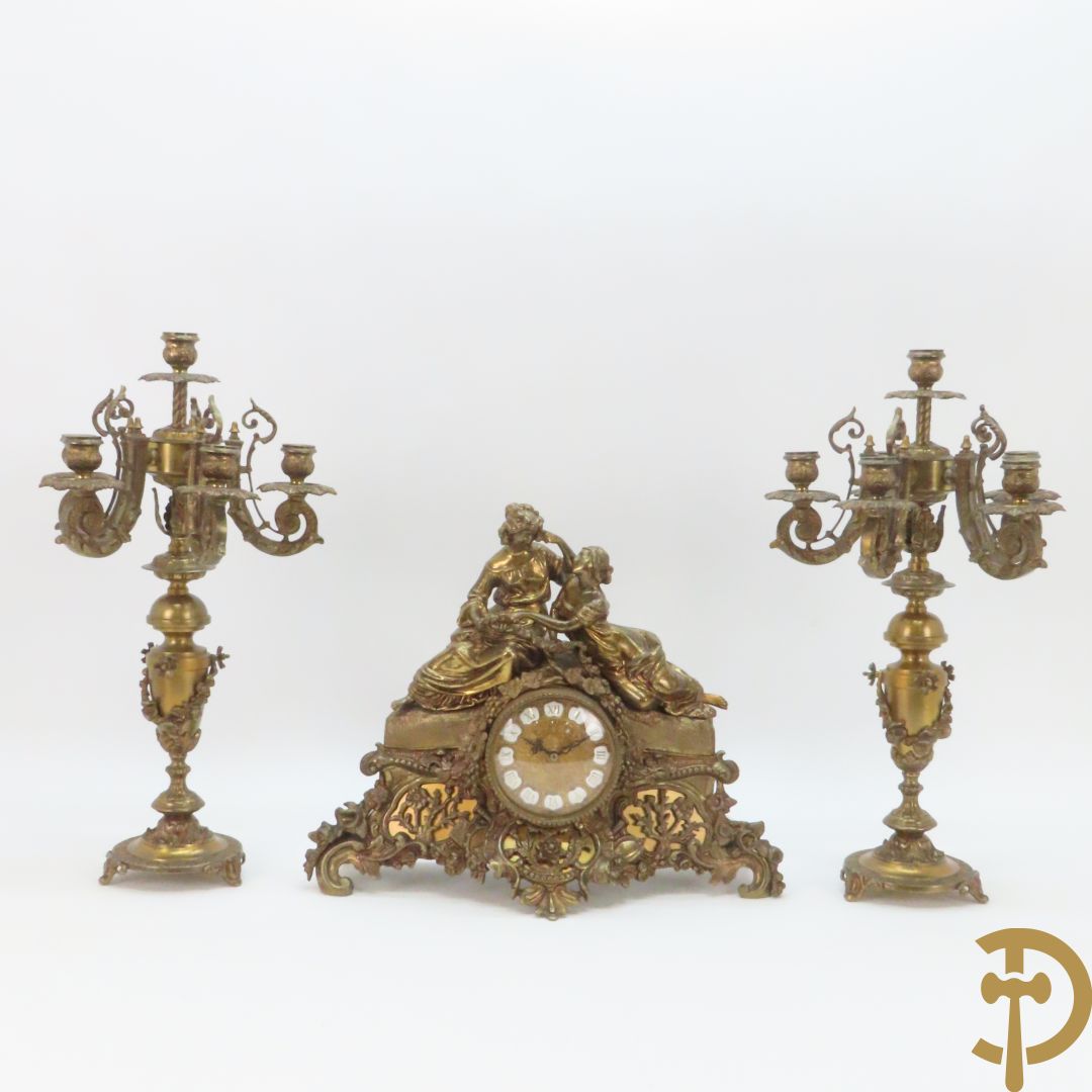 Driedelige bronzen garnituur bestaande uit pendule met 2 dames bovenaan, geflankeerd door paar zesarmige kandelaars