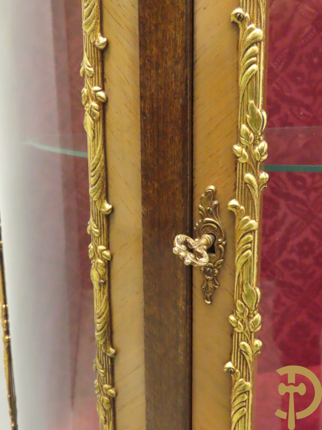 Gebogen notelaren vitrine met bronsbeslag en geanimeerd romantisch tafereel onderaan