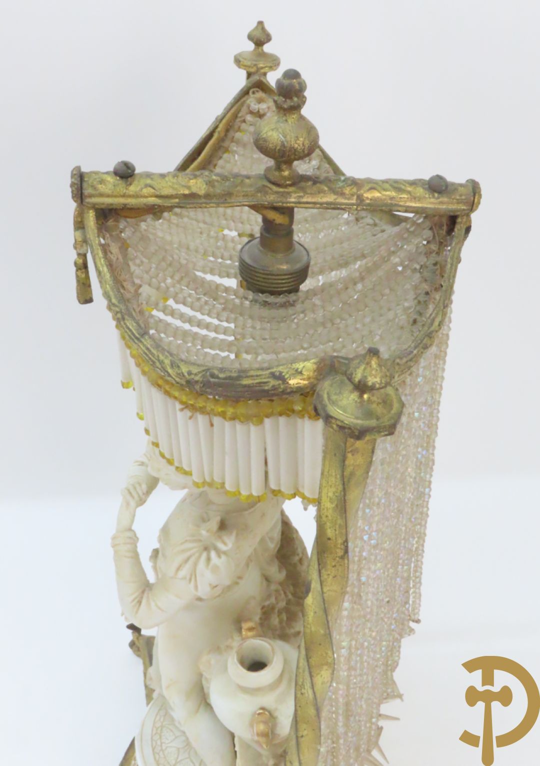 Lieftallig biscuit van romantisch koppel bij amfoor met kleine neergezeten cupido onder koperen baldakijn met kristallen belletjes