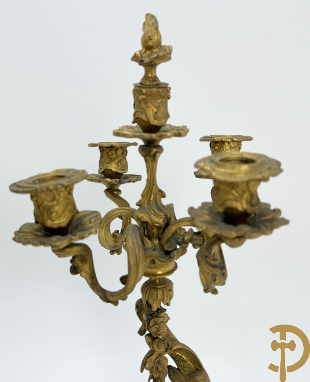 Driedelige vuurvergulde bronzen garnituur, Louis XV stijl, bestaande uit middenstuk met klok omgeven door musicerende cupido