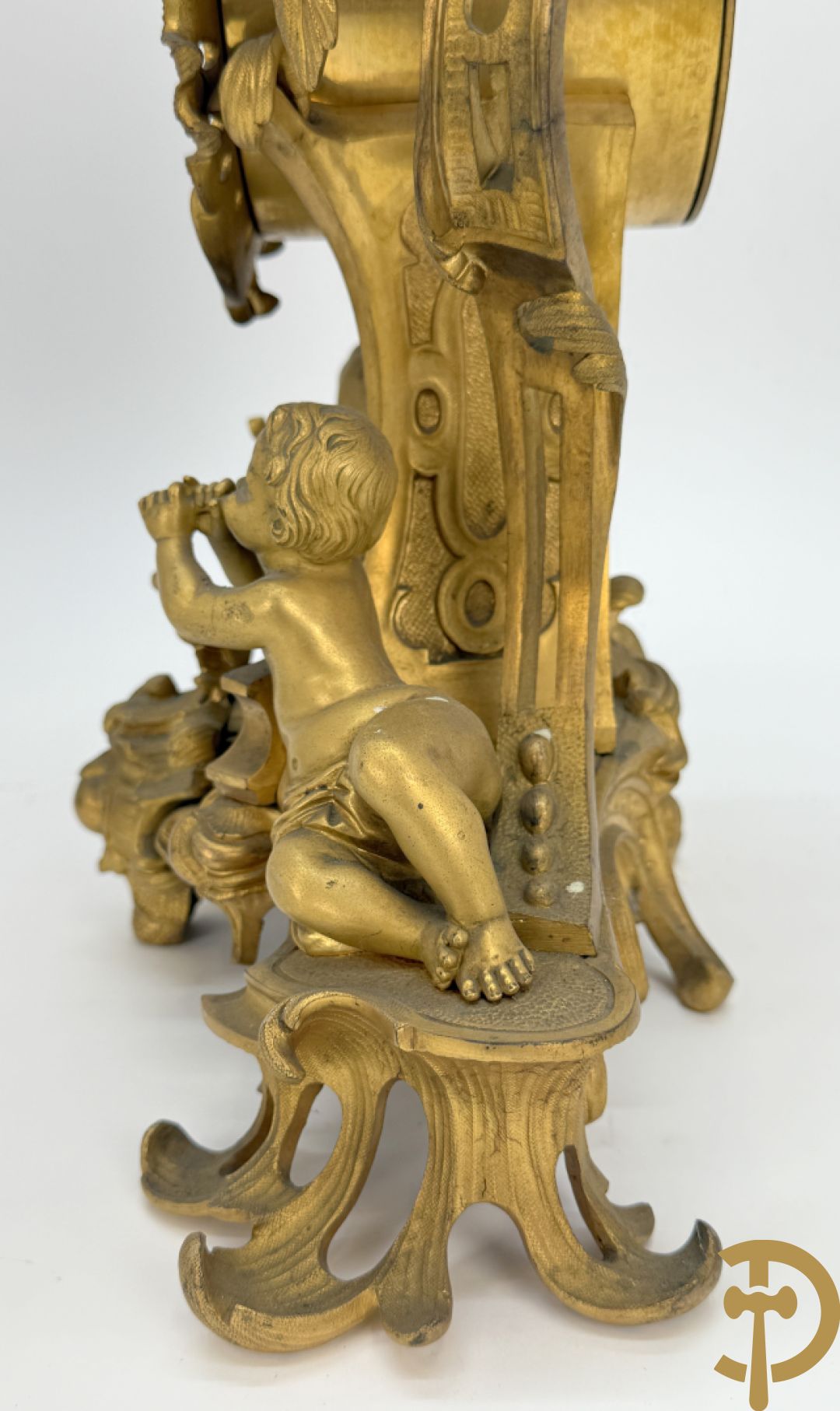 Driedelige vuurvergulde bronzen garnituur, Louis XV stijl, bestaande uit middenstuk met klok omgeven door musicerende cupido