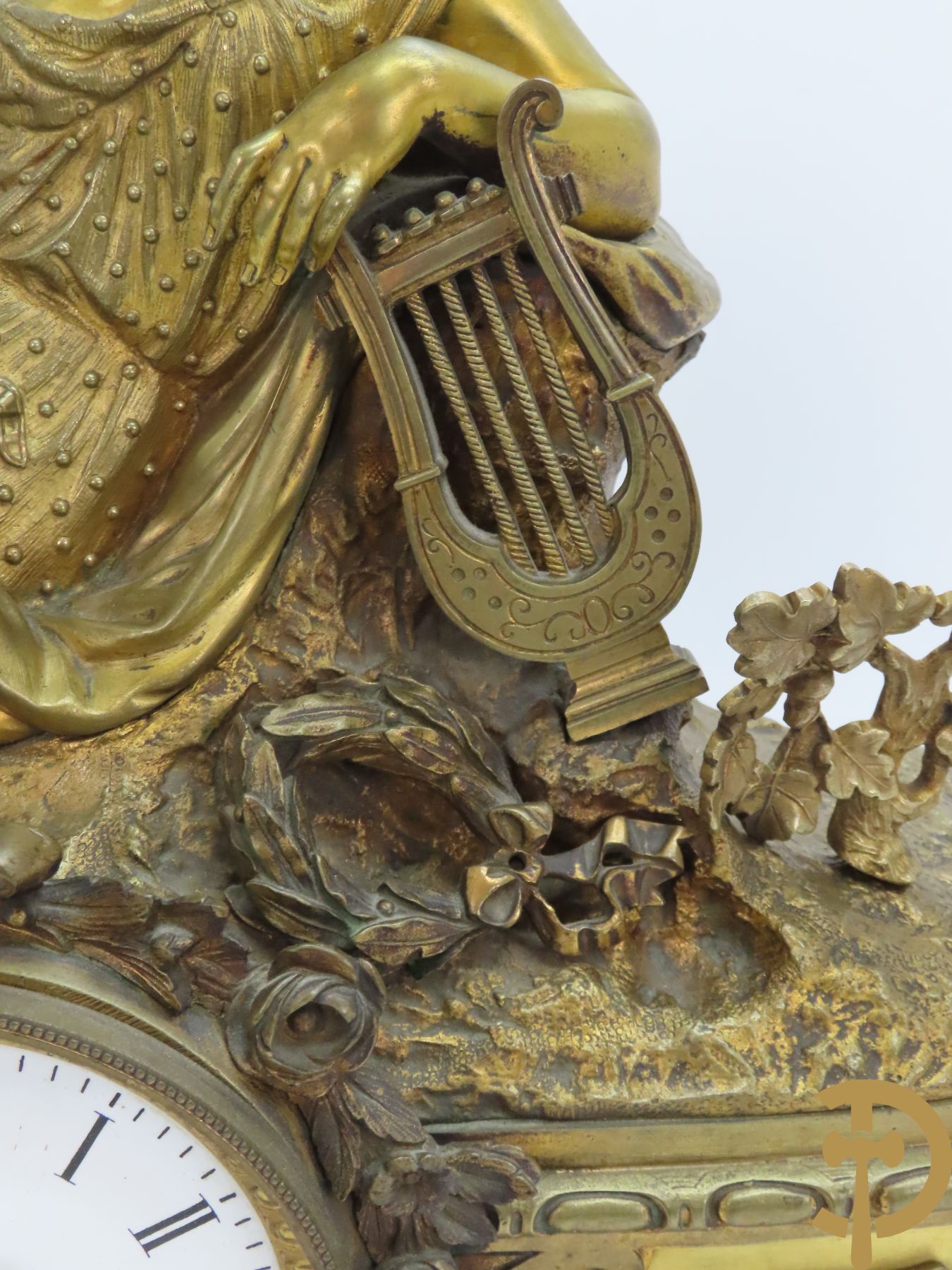 Bronzen schouwstuk met zittende dame met trompet en harp op horloge met muziekinstrumenten