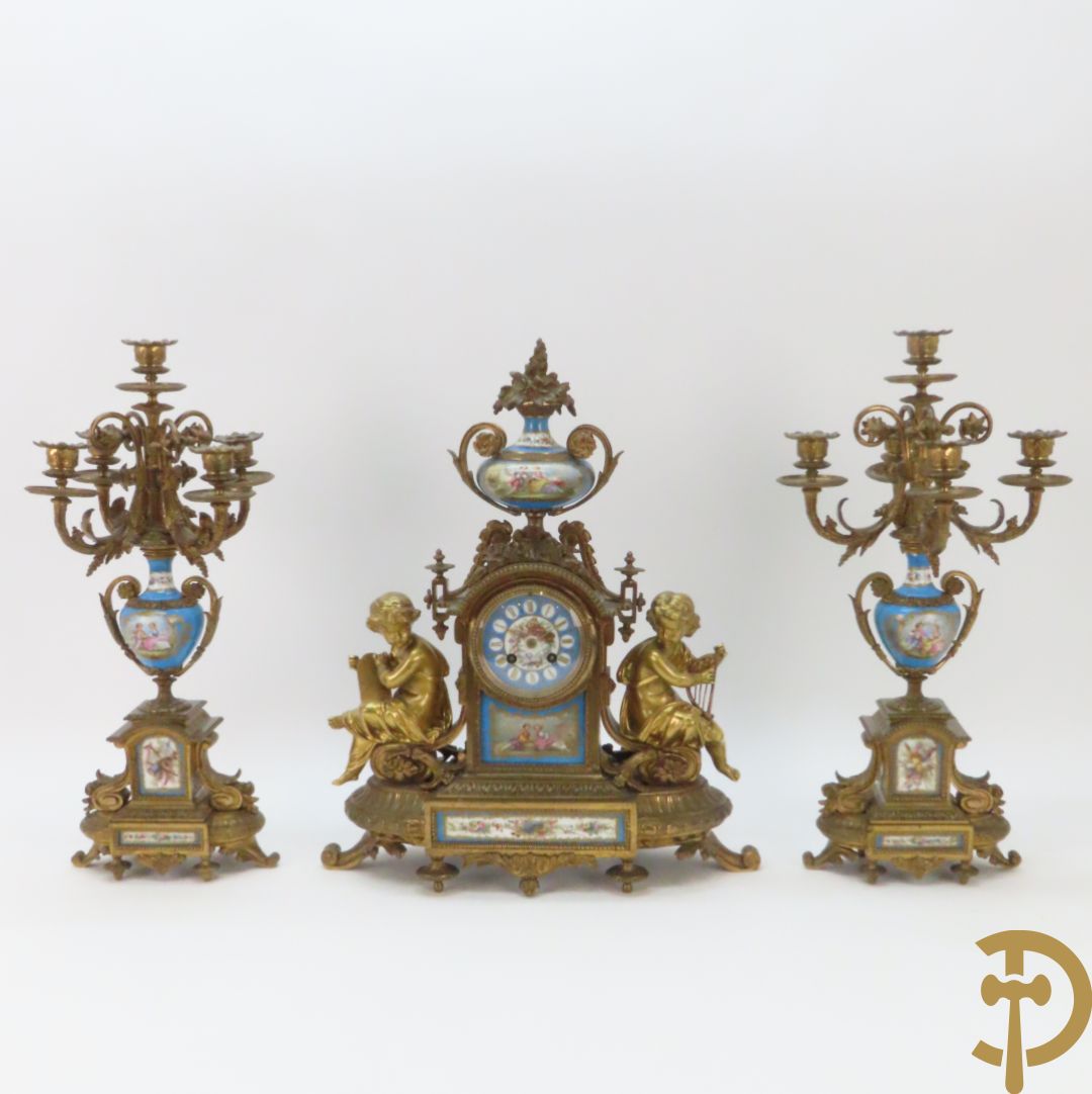 Driedelige bronzen garnituur bezet met Sèvres porselein bestaande uit pendule geflankeerd door paar cupido