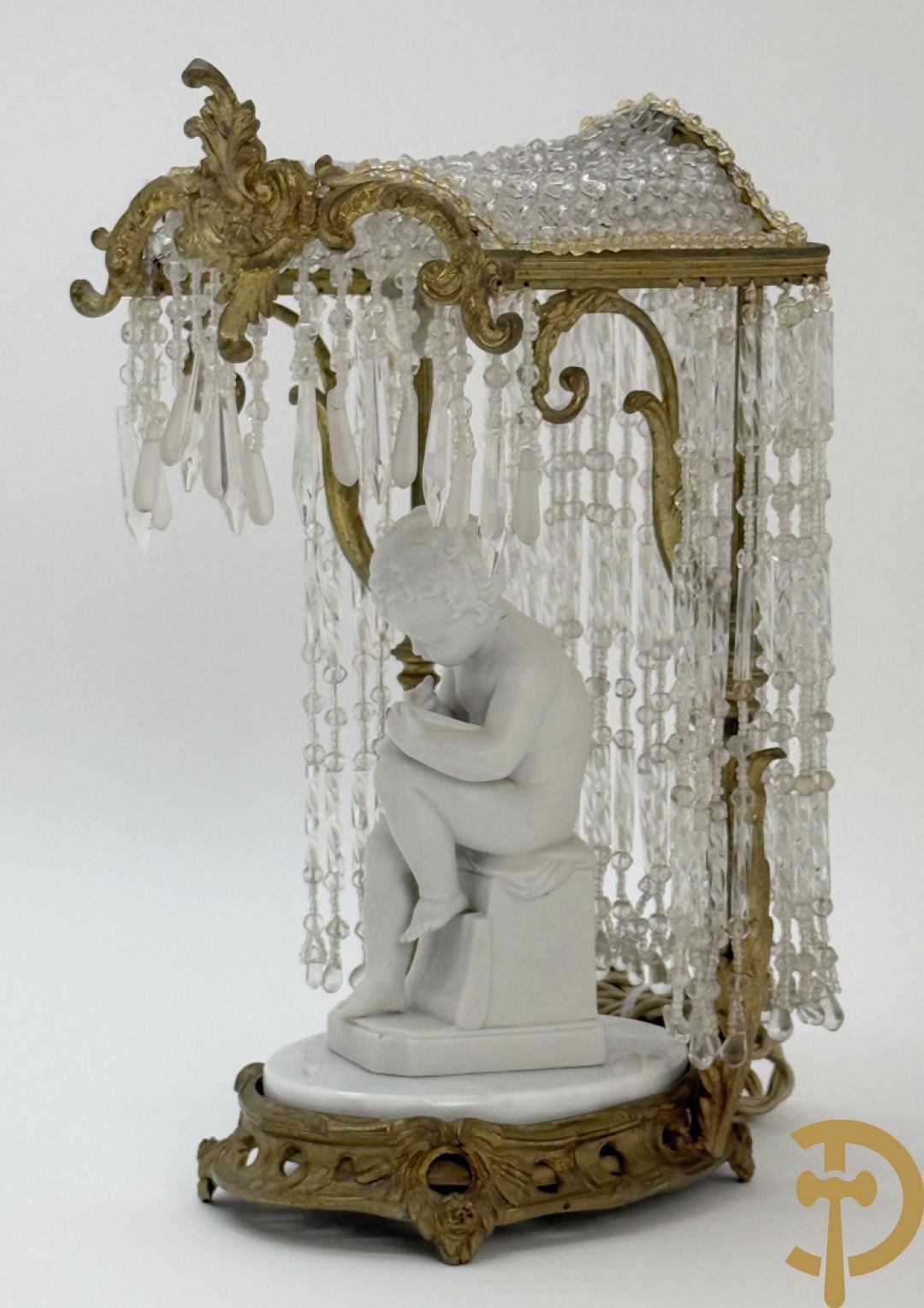 Biscuitbeeld van schrijvende cupido onder bronzen dakje met kristallen bellen bezet - op marmeren sokkel gemonteerd