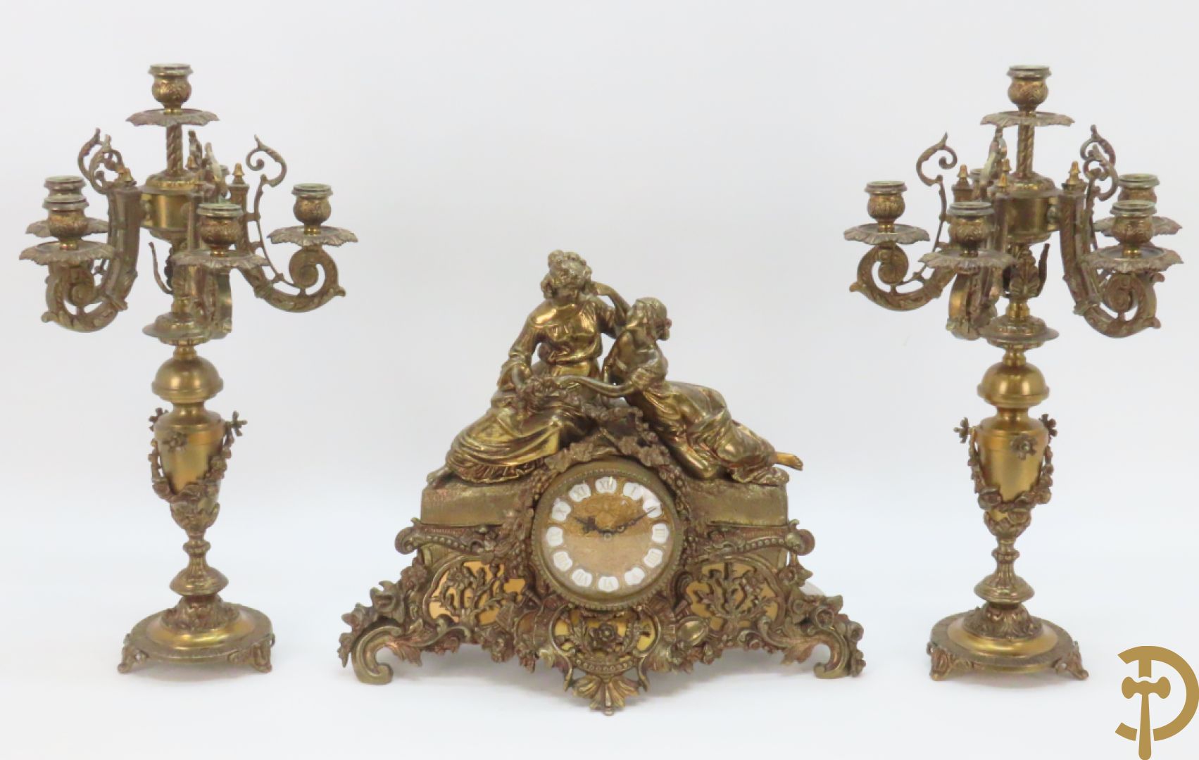 Driedelige bronzen garnituur bestaande uit pendule met 2 dames bovenaan, geflankeerd door paar zesarmige kandelaars