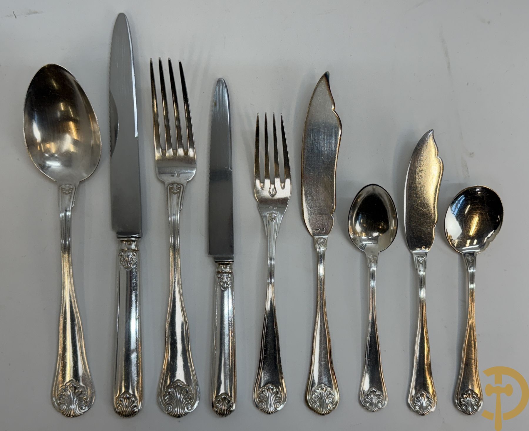 Massief zilveren bestek Wolfers bestaande uit 12 vorken (979 gram), 12 lepels (1028 gram), 11 messen, 12 visvorken (553 gram), 12 vismessen (690 gram), 12 dessertmessen, 10 koffielepels (296 gram), 12 ijslepels (369 gram), 3 botermesjes en scheplepeltje (165 gram), 5  grote stukken (samen 557 gram) waarvan slacouvert, 2 taartscheppen en wildvork + sauslepel met zelfde decor maar Metal Blanc