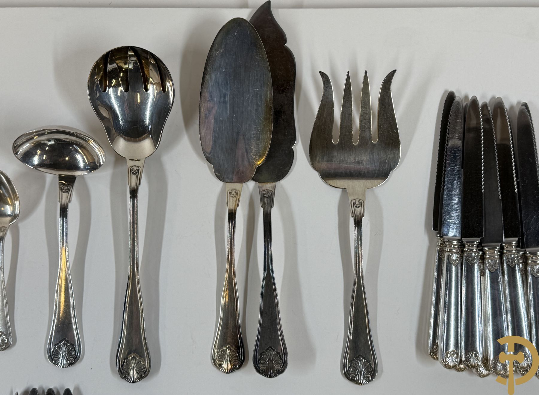 Massief zilveren bestek Wolfers bestaande uit 12 vorken (979 gram), 12 lepels (1028 gram), 11 messen, 12 visvorken (553 gram), 12 vismessen (690 gram), 12 dessertmessen, 10 koffielepels (296 gram), 12 ijslepels (369 gram), 3 botermesjes en scheplepeltje (165 gram), 5  grote stukken (samen 557 gram) waarvan slacouvert, 2 taartscheppen en wildvork + sauslepel met zelfde decor maar Metal Blanc