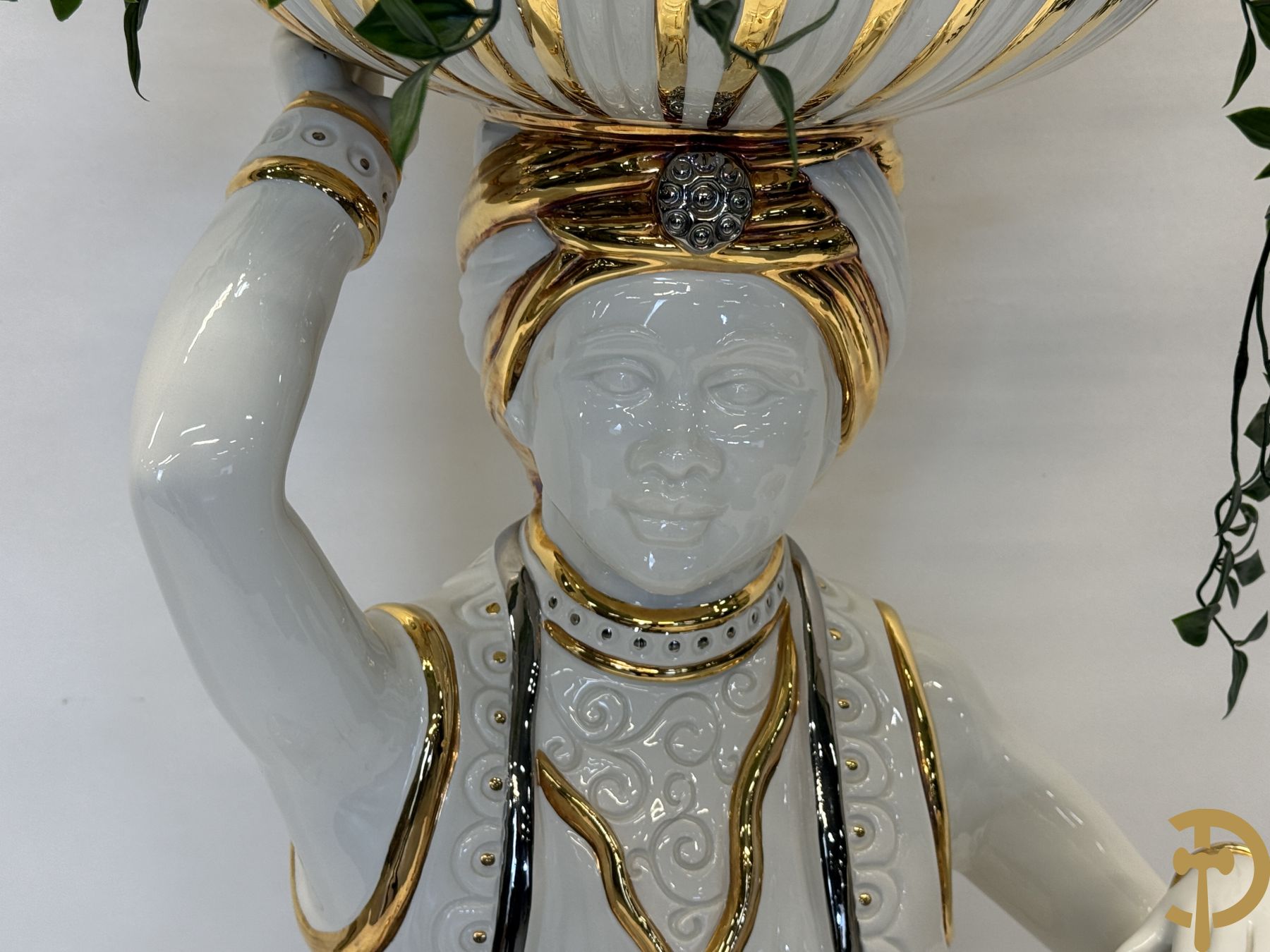 Porseleinen sierbeeld van olifant als staander met daarboven jongeman met bloemencachepot