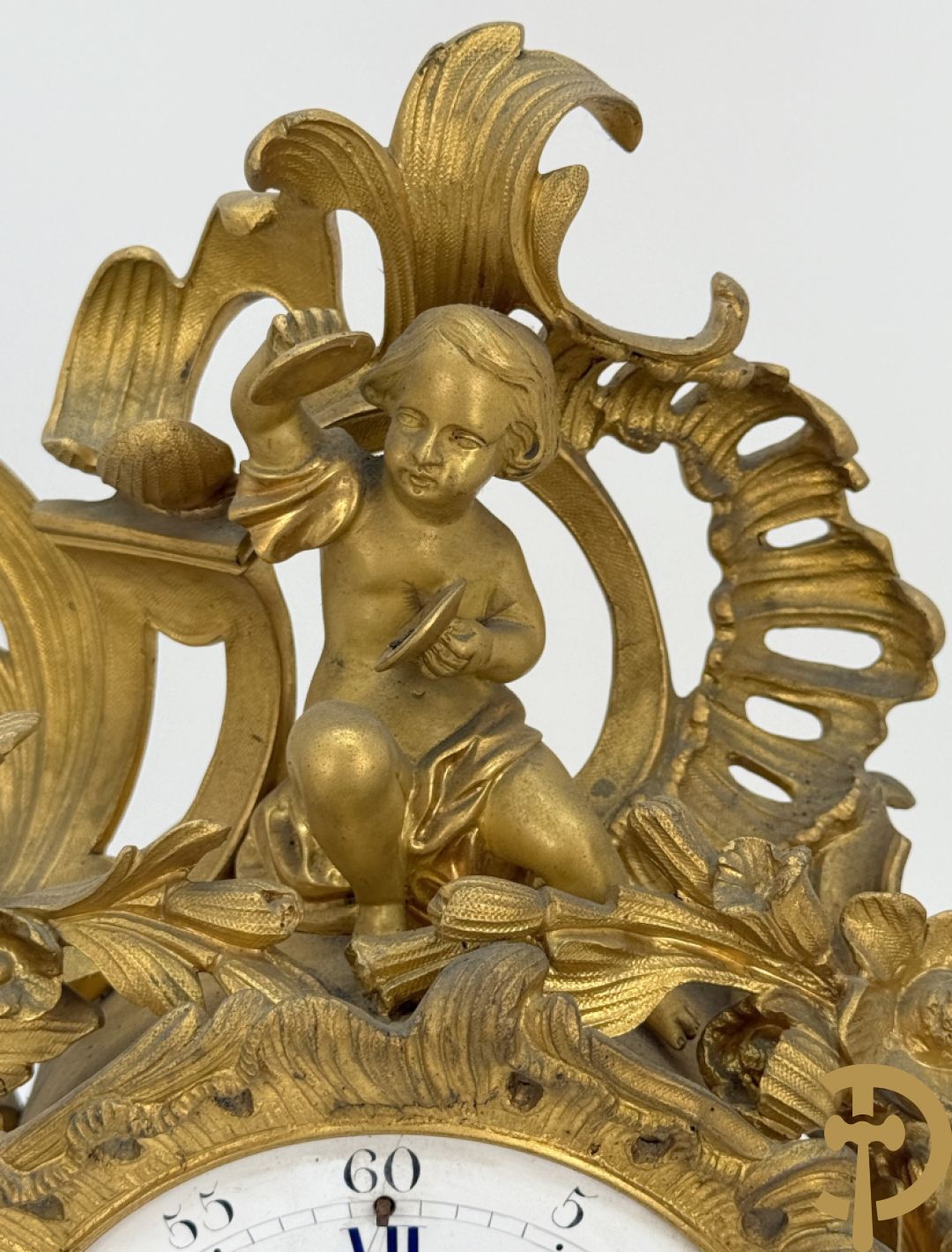 Driedelige vuurvergulde bronzen garnituur, Louis XV stijl, bestaande uit middenstuk met klok omgeven door musicerende cupido