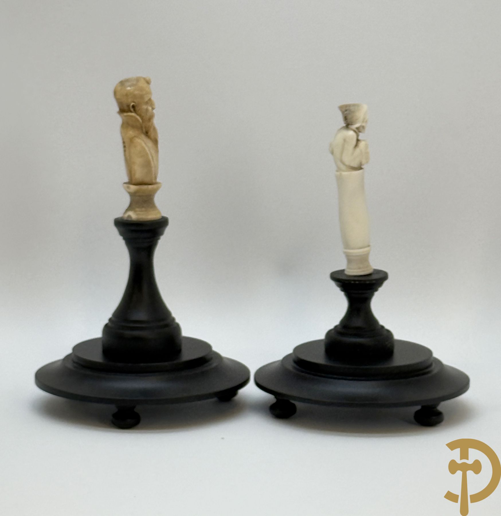 Twee handgesculpteerde hertegeweien in de vorm van een doodskop onder globe