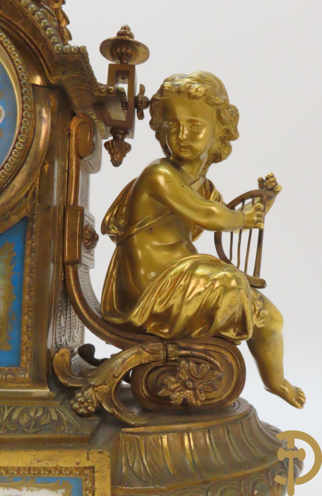 Driedelige bronzen garnituur bezet met Sèvres porselein bestaande uit pendule geflankeerd door paar cupido