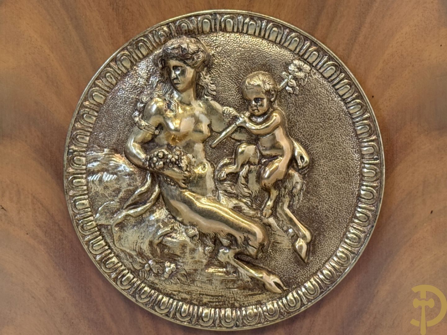 Notelaren vitrine met afgeronde zijkanten, bezet met bronzen plakkettes van dame en cupido