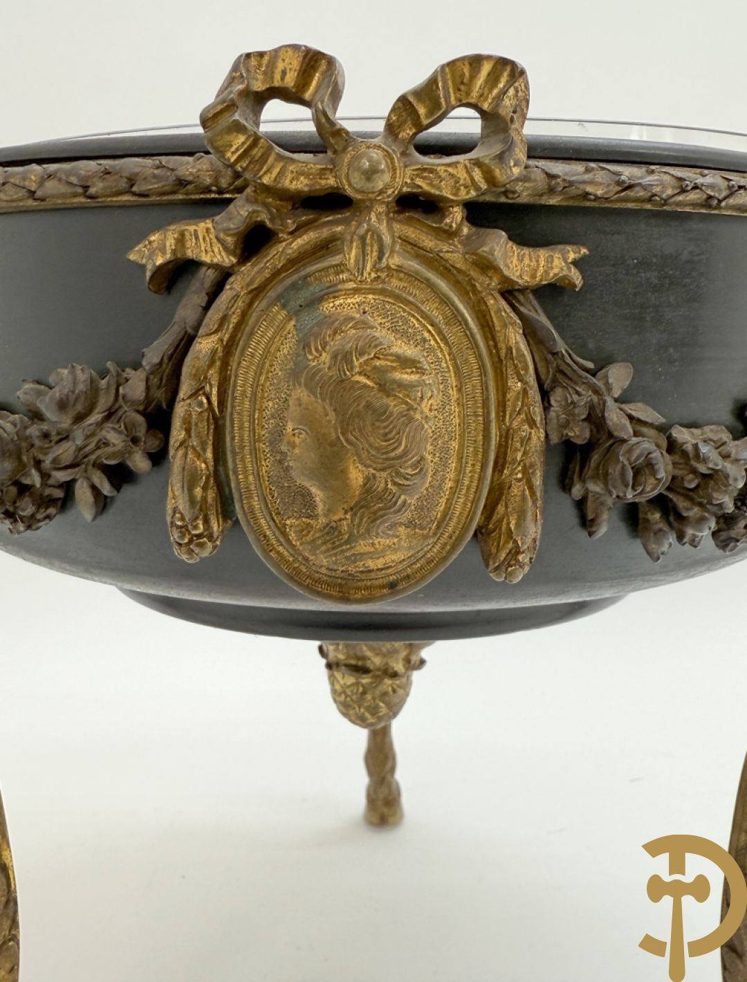 Bronzen coupe op 3 bokkepoten met ramskoppen  bezet en verbonden door guirlandes met medaillon