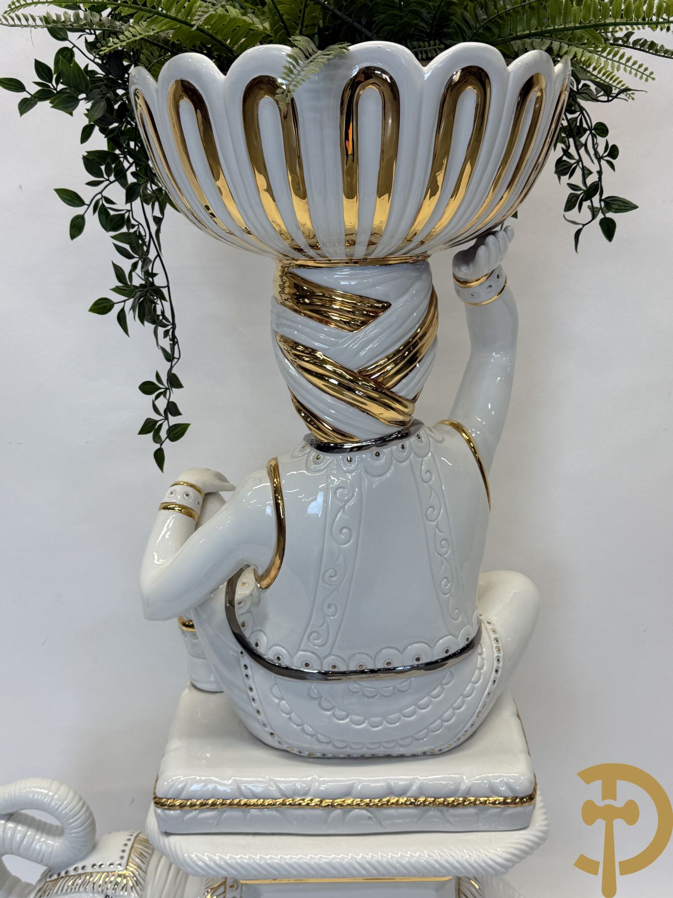 Porseleinen sierbeeld van olifant als staander met daarboven jongeman met bloemencachepot