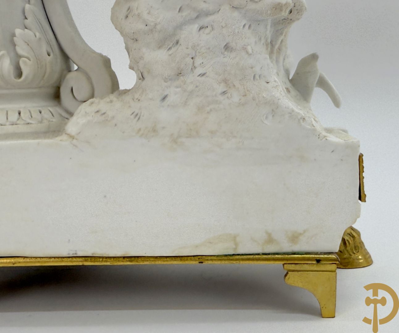 Driedelige porseleinen garnituur met bronsbeslag bestaande uit pendule met dame en amfoor geflankeerd door paar kandelaars bezet met personages