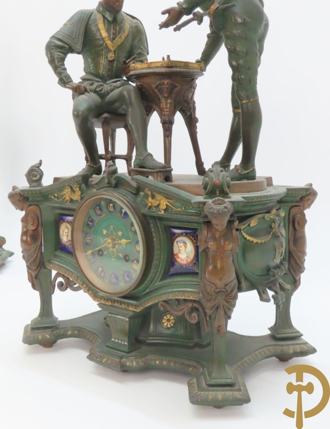 Driedelige kunstbronzen garnituur bestaande uit pendule met paar schakende edelheren, bezet met kariatiden - geflankeerd door paar driearmige kandelaars gehouden door 2 edelheren