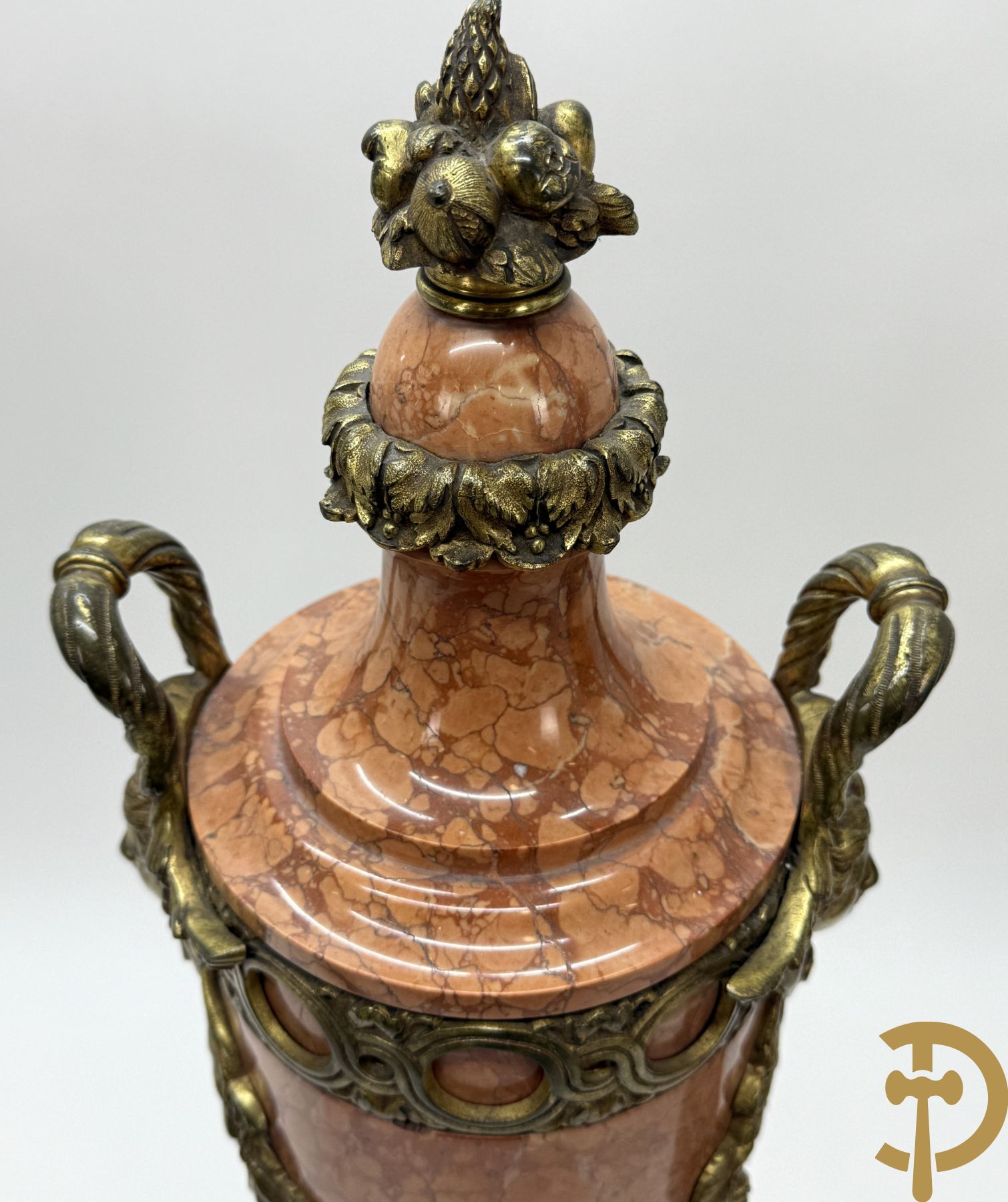 Paar oranje/rode marmeren cassolettes, zijdelings bezet met dameshoofden dragende een guirlande van bloemen - bovenaan met bloementroffee