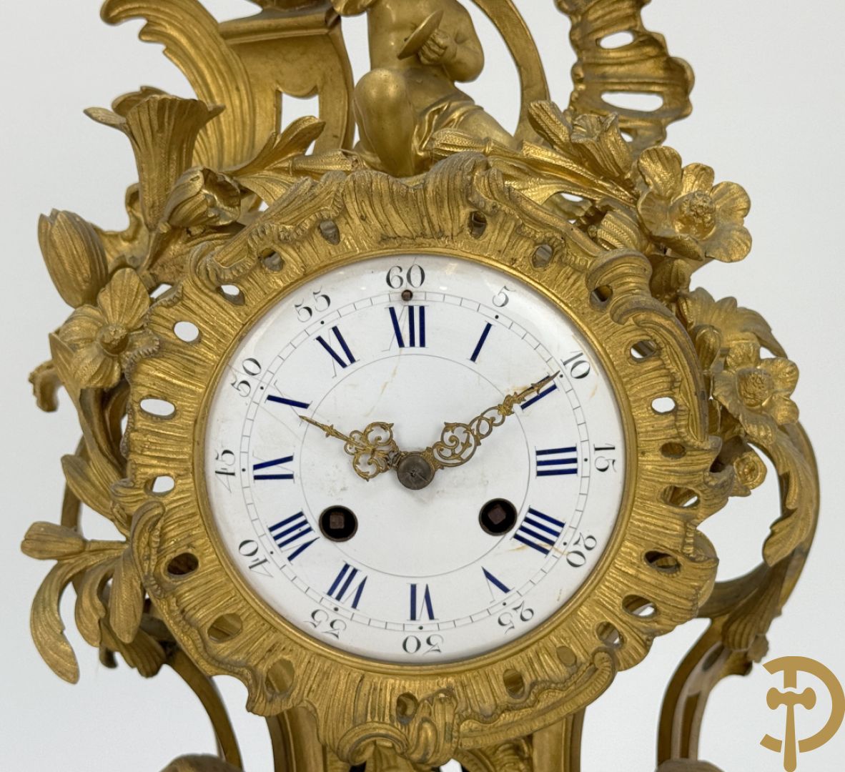 Driedelige vuurvergulde bronzen garnituur, Louis XV stijl, bestaande uit middenstuk met klok omgeven door musicerende cupido