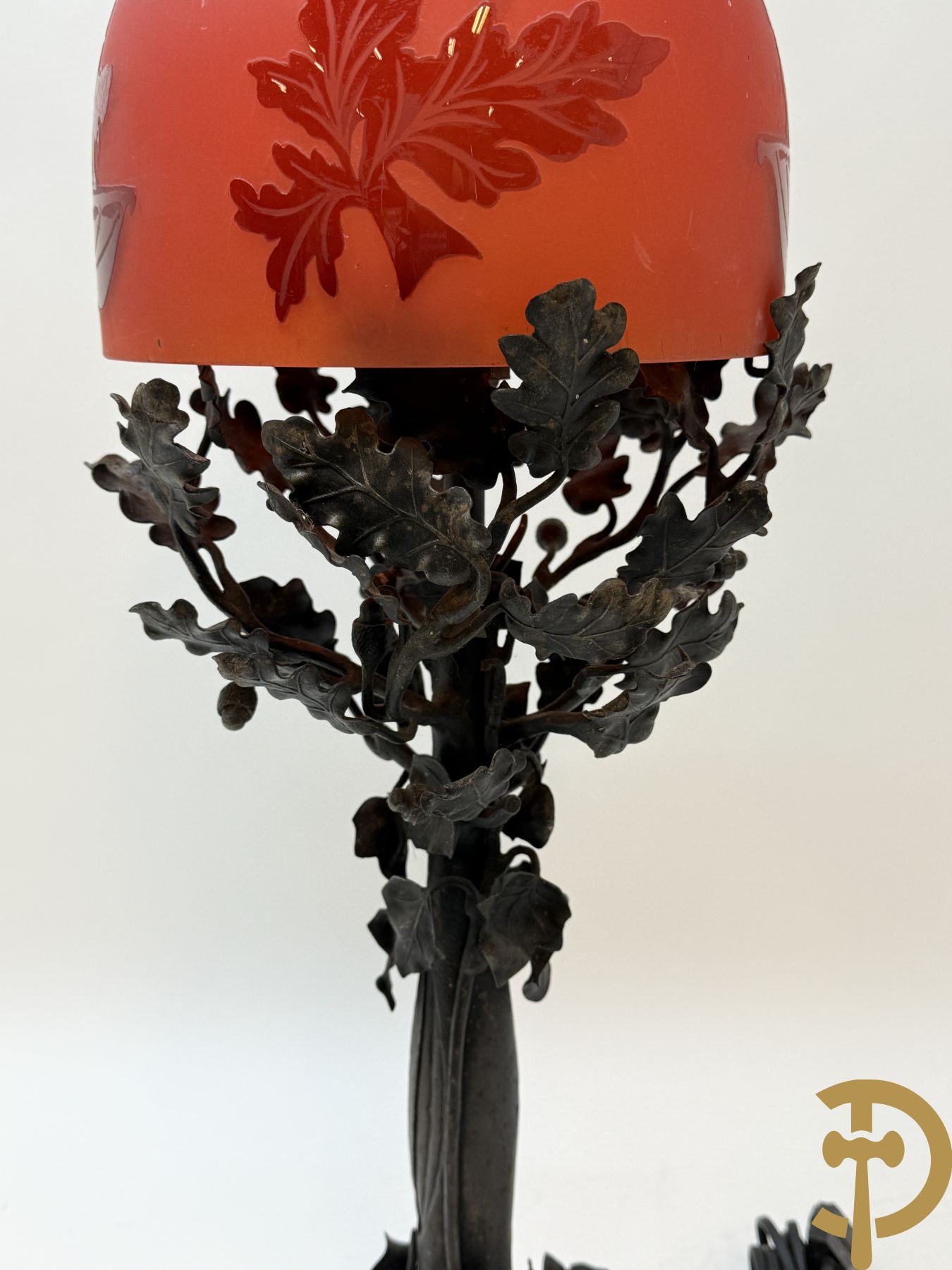 Smeedijzeren lampadaire in boomvorm met eikebladranken, Th. Massé getekend, met rood/oranje gezuurde kap met decor van cupido