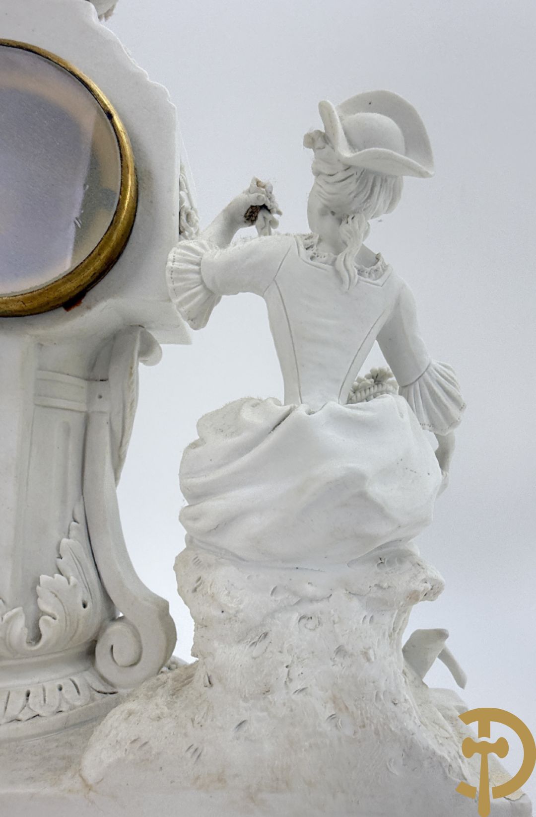 Driedelige porseleinen garnituur met bronsbeslag bestaande uit pendule met dame en amfoor geflankeerd door paar kandelaars bezet met personages