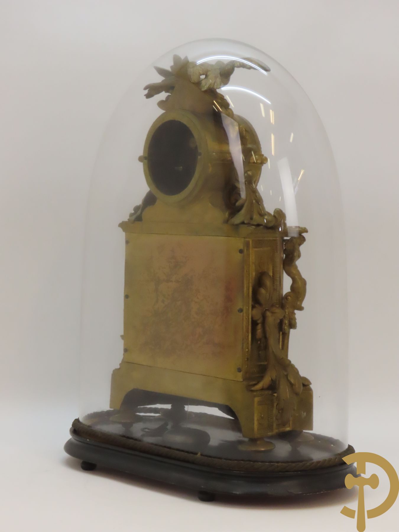 Vergulde pendule in zamak, wijzerplaat bezet met porseleinen plakkettes - bovenaan met vogelpaar, zijdelings met kariathyden houdende een bloementroffee - onder glazen stolp