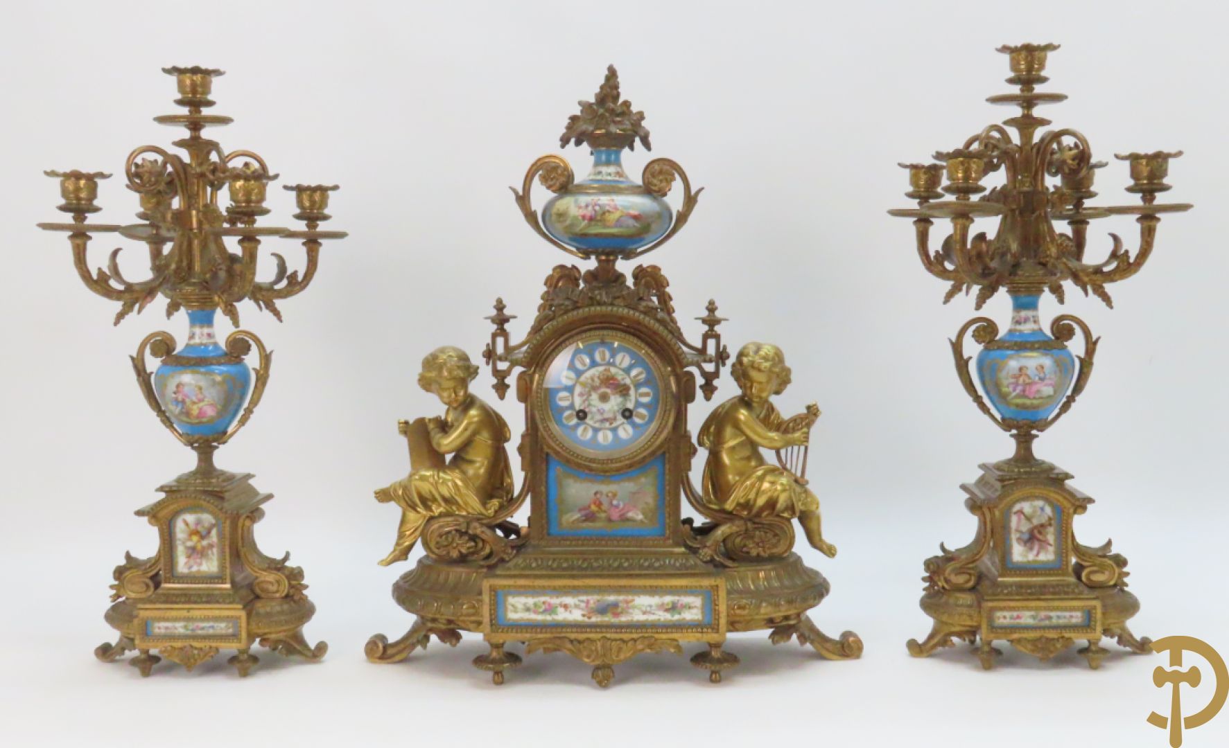 Driedelige bronzen garnituur bezet met Sèvres porselein bestaande uit pendule geflankeerd door paar cupido