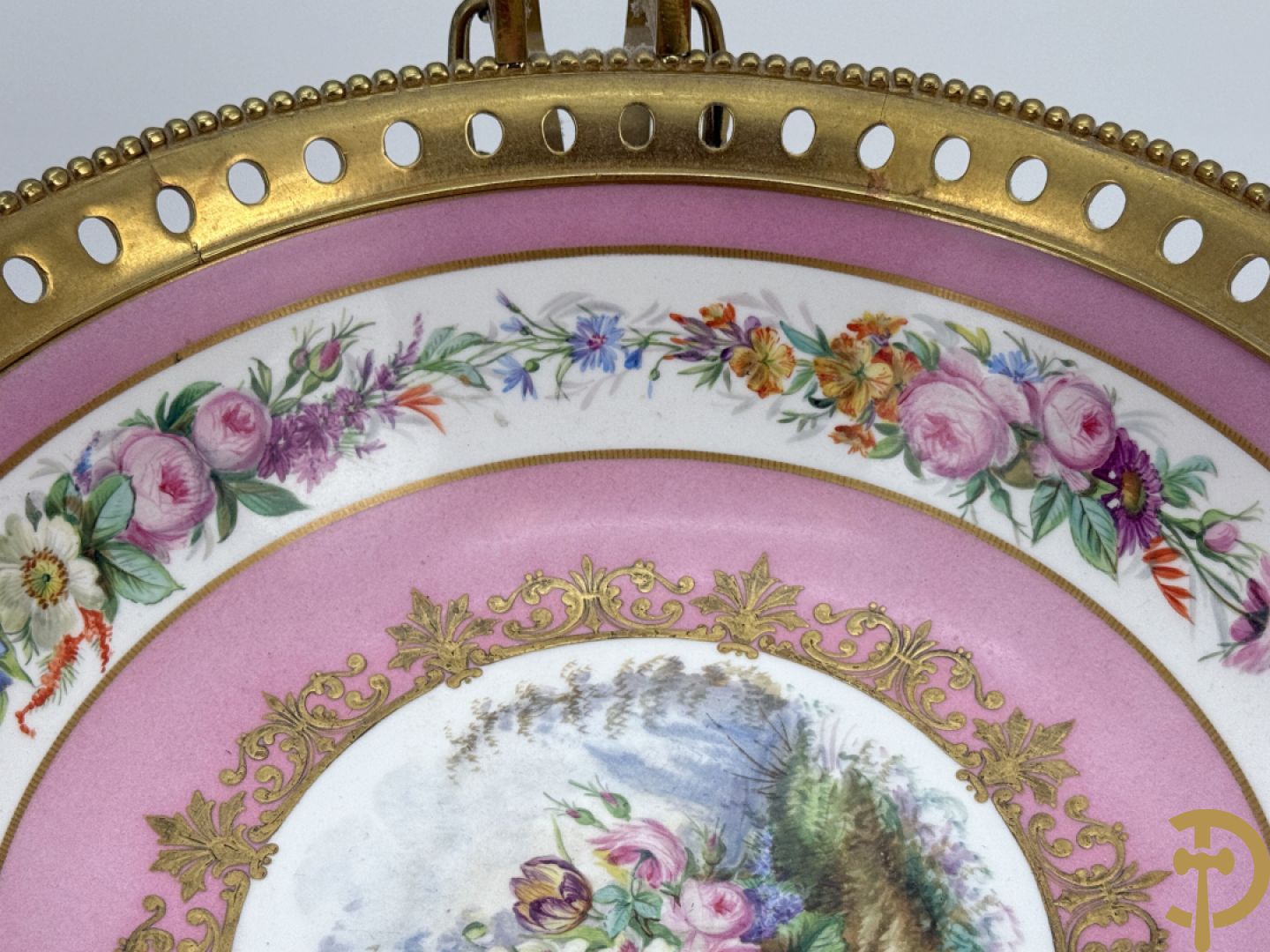 Porseleinen coupe met centraal tafereel en omringd met bloemendecor, gevat in bronzen houder