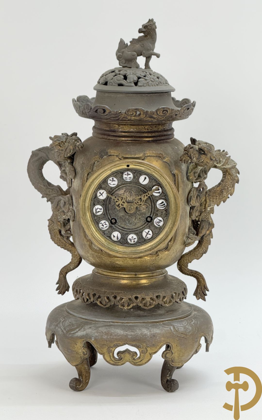 Aziatische pendule in zamak, zijdelings bezet met drakendecor en bovenaan met mythologisch figuur