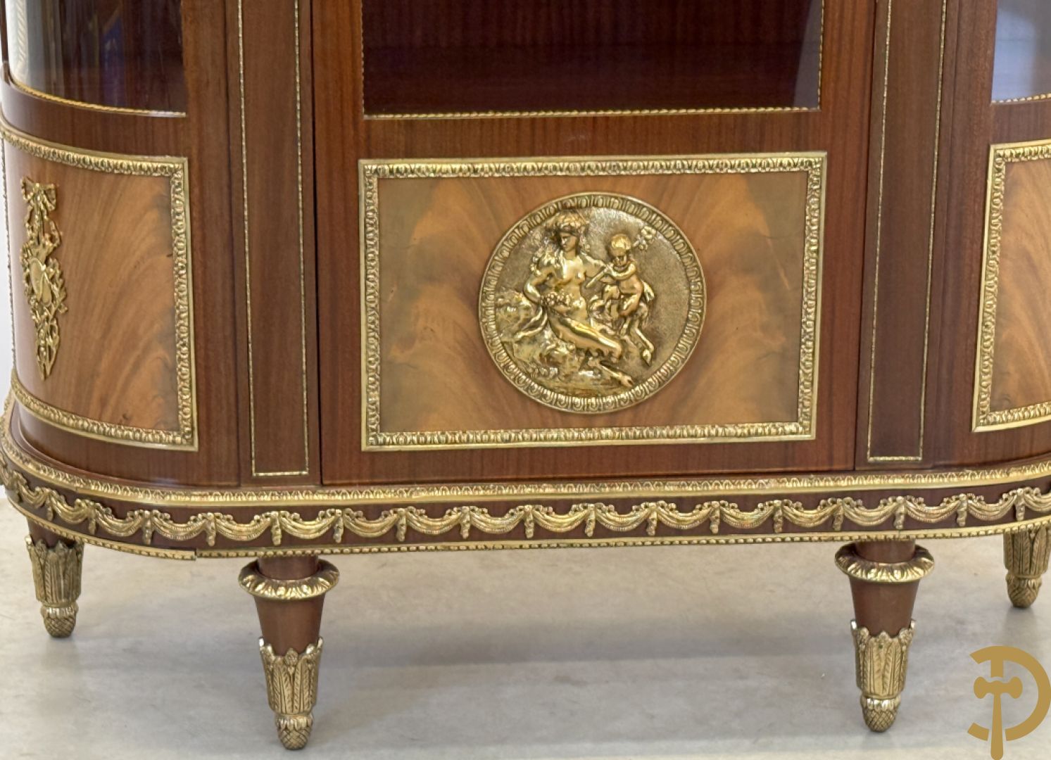 Notelaren vitrine met afgeronde zijkanten, bezet met bronzen plakkettes van dame en cupido