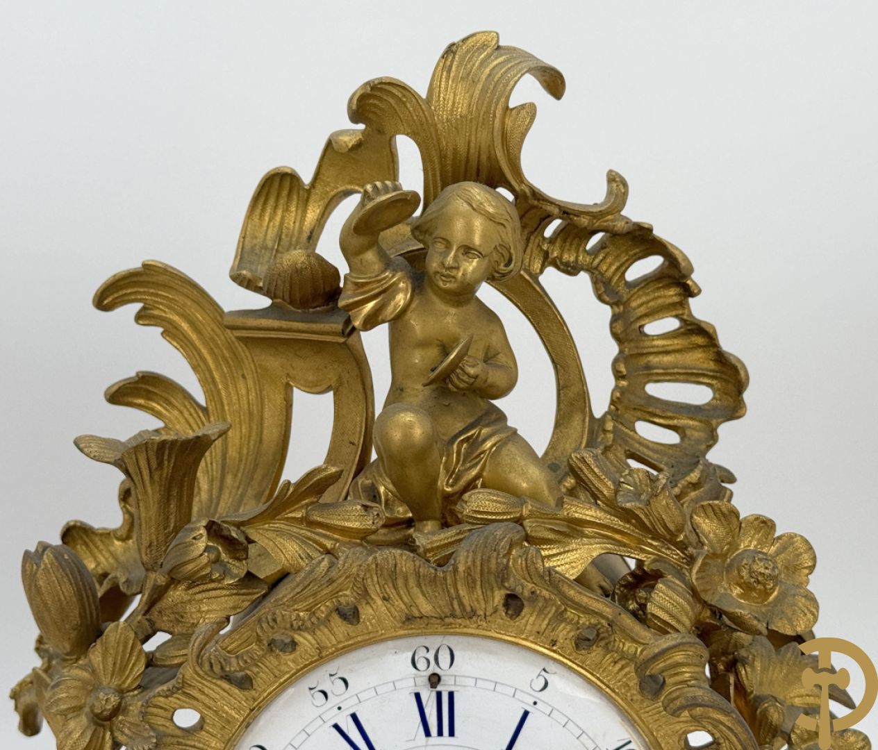 Driedelige vuurvergulde bronzen garnituur, Louis XV stijl, bestaande uit middenstuk met klok omgeven door musicerende cupido