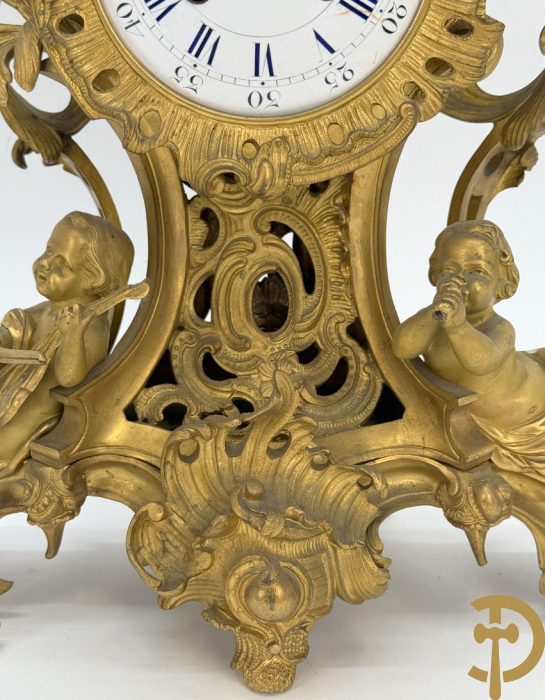 Driedelige vuurvergulde bronzen garnituur, Louis XV stijl, bestaande uit middenstuk met klok omgeven door musicerende cupido