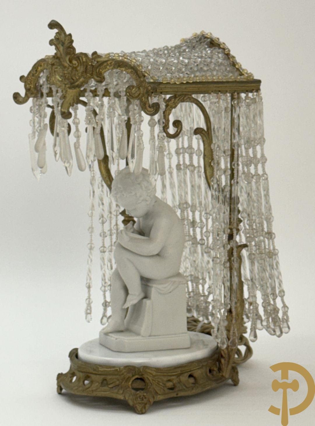 Biscuitbeeld van schrijvende cupido onder bronzen dakje met kristallen bellen bezet - op marmeren sokkel gemonteerd