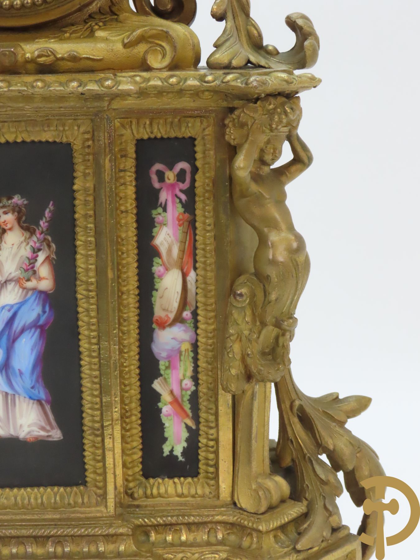 Vergulde pendule in zamak, wijzerplaat bezet met porseleinen plakkettes - bovenaan met vogelpaar, zijdelings met kariathyden houdende een bloementroffee - onder glazen stolp