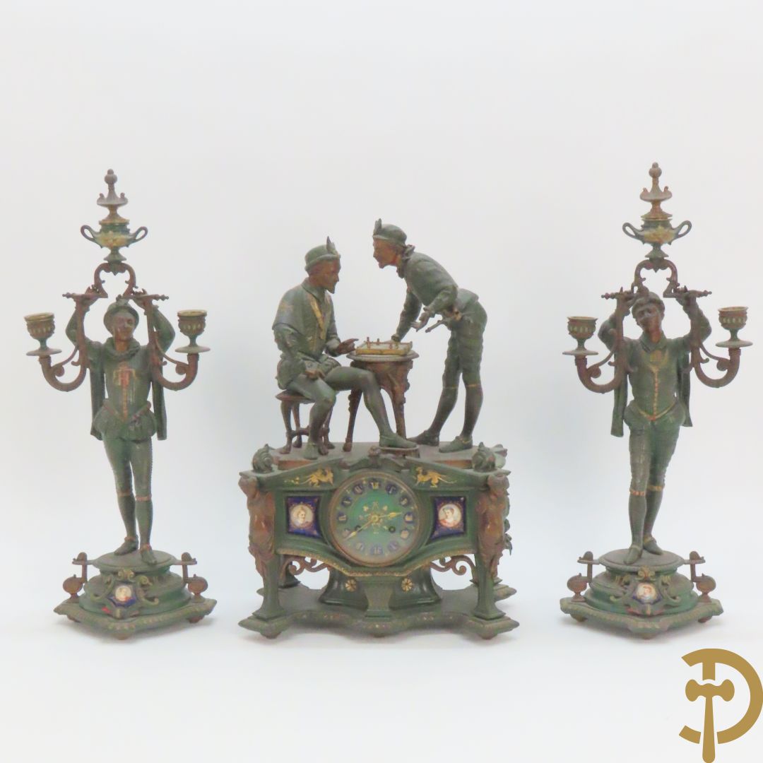 Driedelige kunstbronzen garnituur bestaande uit pendule met paar schakende edelheren, bezet met kariatiden - geflankeerd door paar driearmige kandelaars gehouden door 2 edelheren