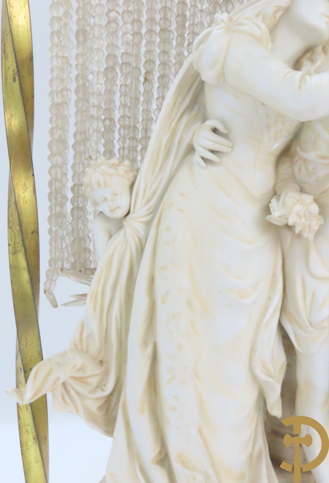 Lieftallig biscuit van romantisch koppel bij amfoor met kleine neergezeten cupido onder koperen baldakijn met kristallen belletjes