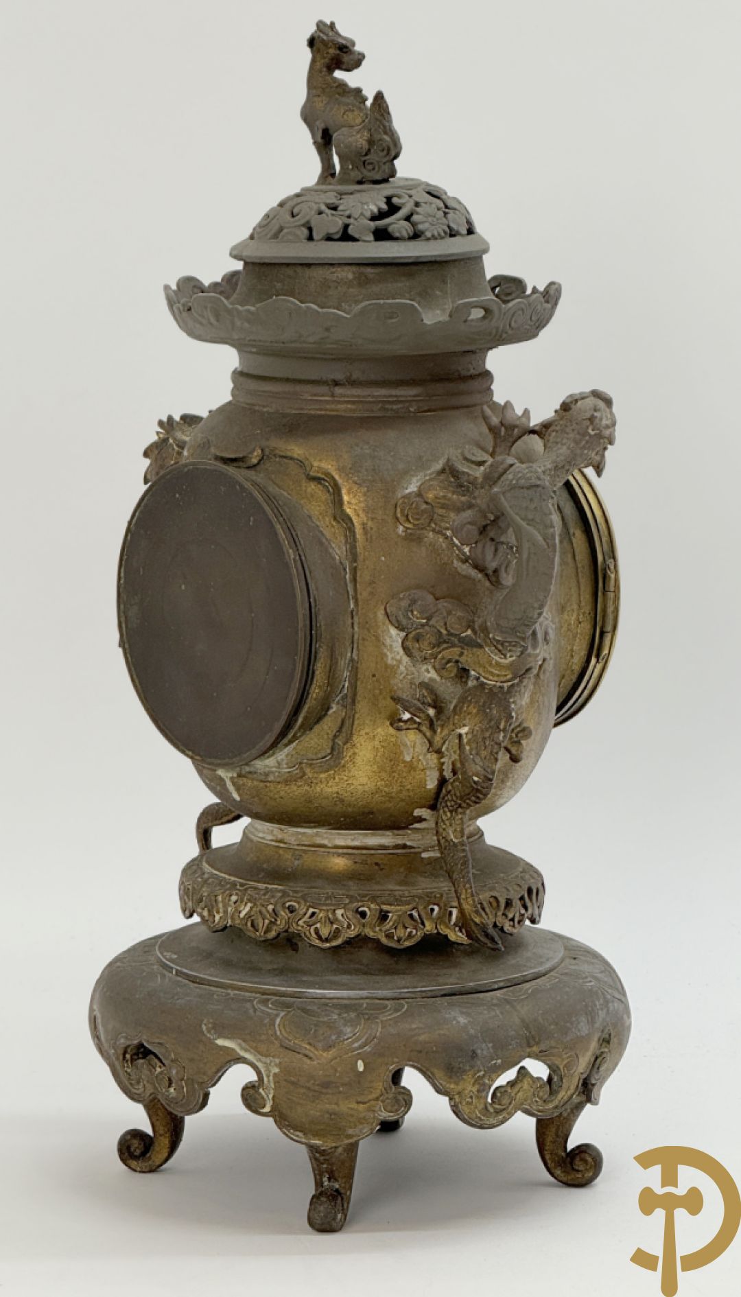 Aziatische pendule in zamak, zijdelings bezet met drakendecor en bovenaan met mythologisch figuur