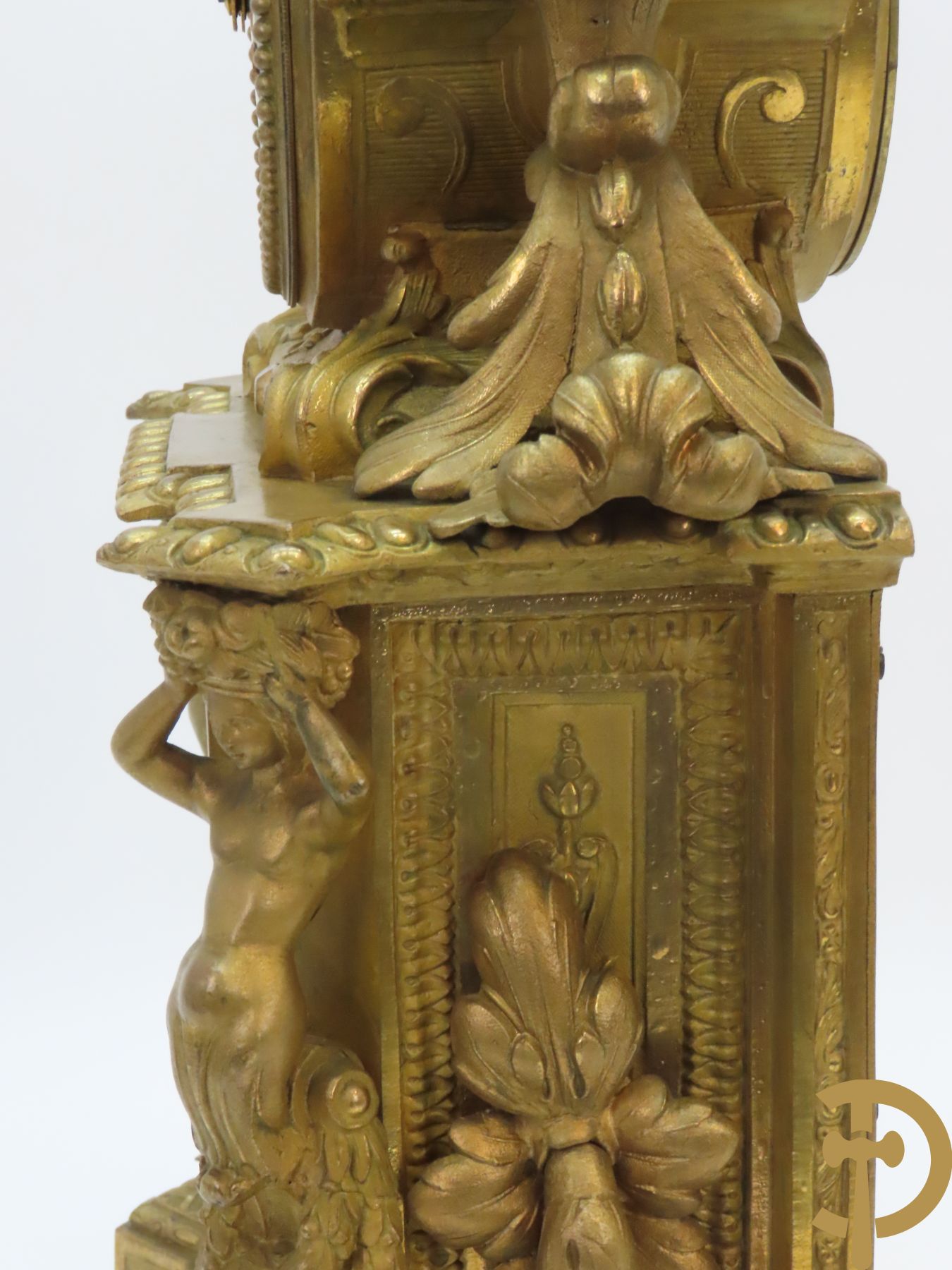 Vergulde pendule in zamak, wijzerplaat bezet met porseleinen plakkettes - bovenaan met vogelpaar, zijdelings met kariathyden houdende een bloementroffee - onder glazen stolp