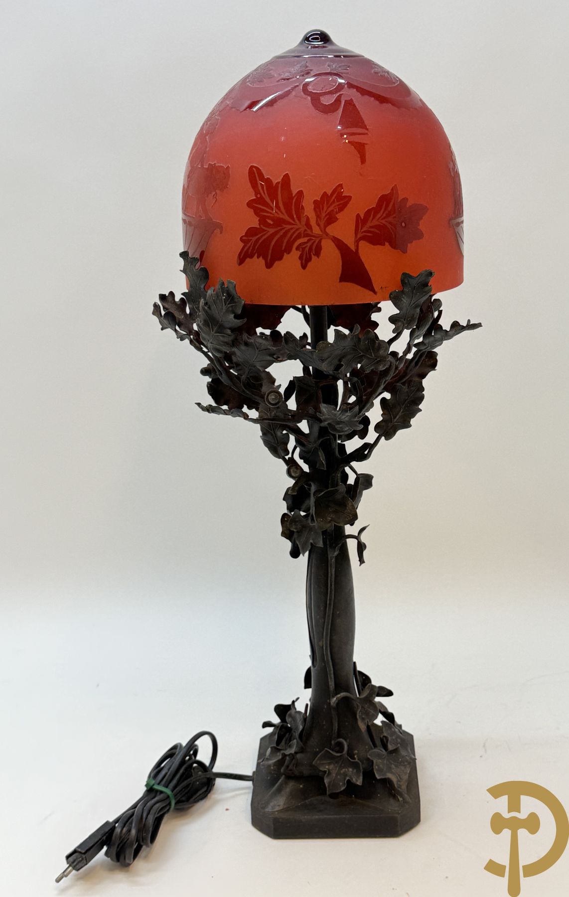 Smeedijzeren lampadaire in boomvorm met eikebladranken, Th. Massé getekend, met rood/oranje gezuurde kap met decor van cupido