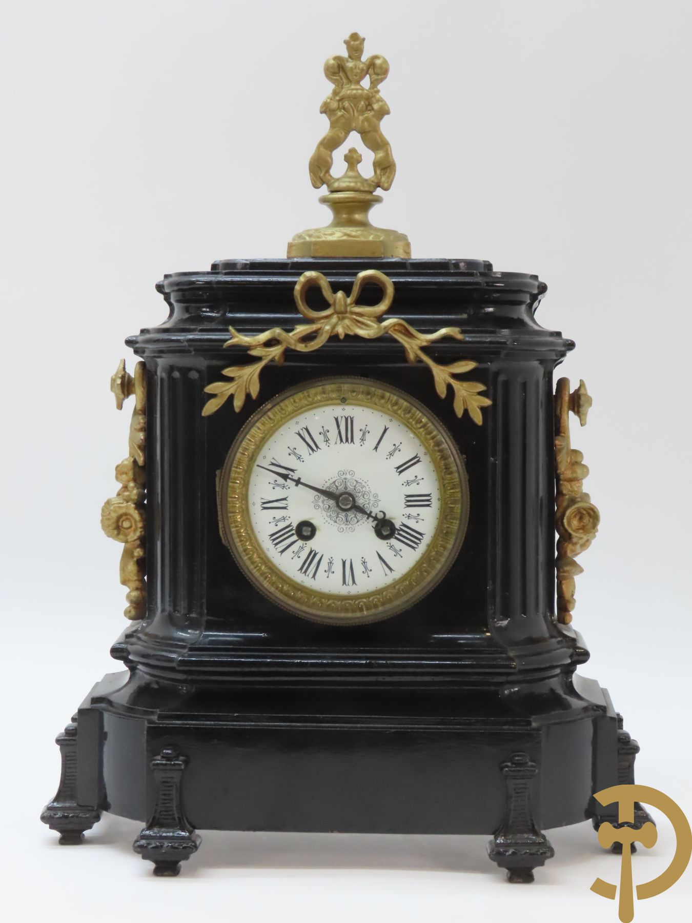 Gepatineerde gietijzeren pendule met bloemenmotieven en Louis XVI strik, bovenaan bekroond met ornament