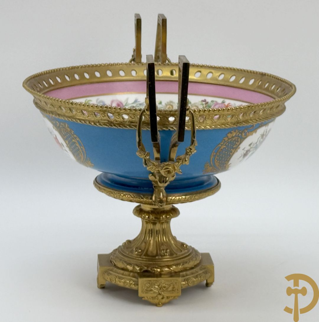 Porseleinen coupe met centraal tafereel en omringd met bloemendecor, gevat in bronzen houder