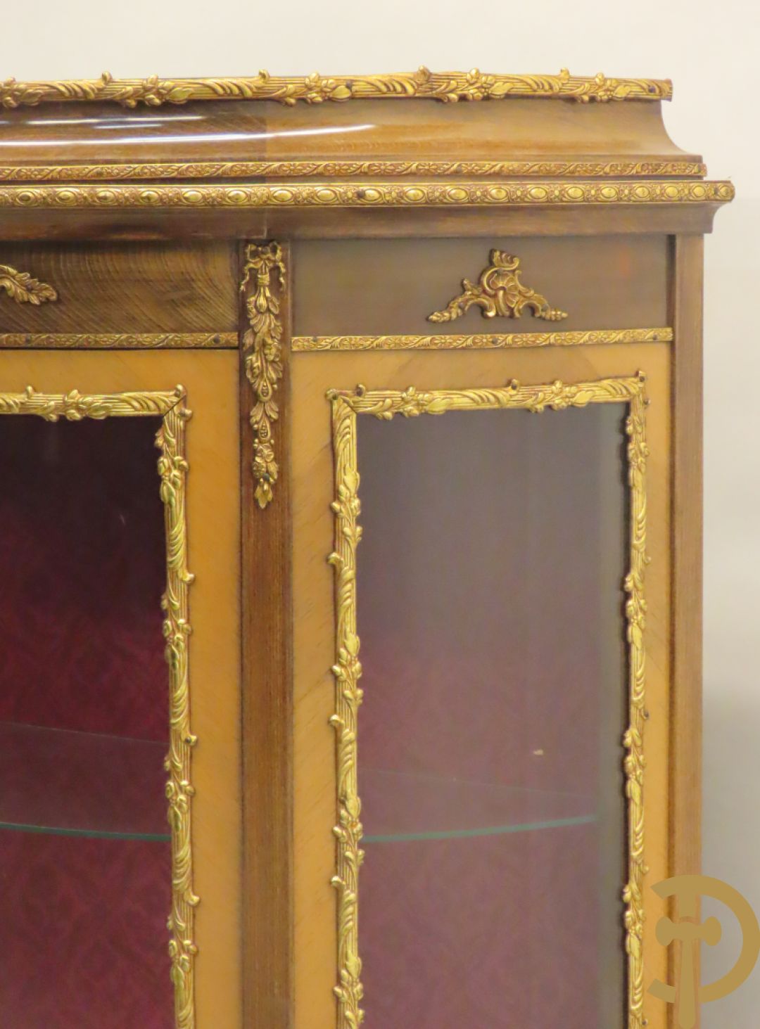 Gebogen notelaren vitrine met bronsbeslag en geanimeerd romantisch tafereel onderaan