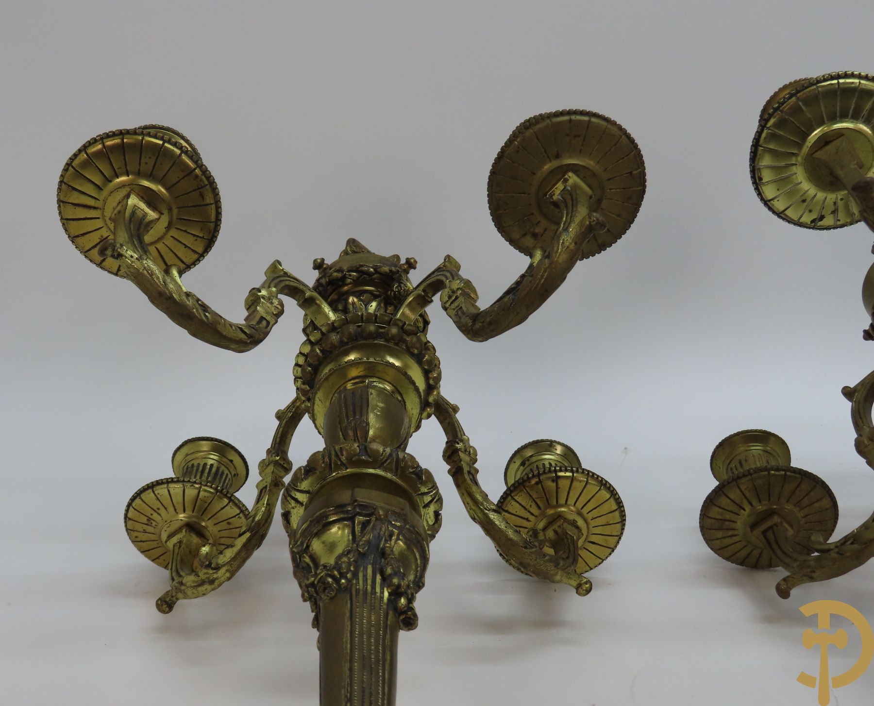 Paar bronzen Louis XVI vierarmige kandelaars bezet met toorts bovenaan