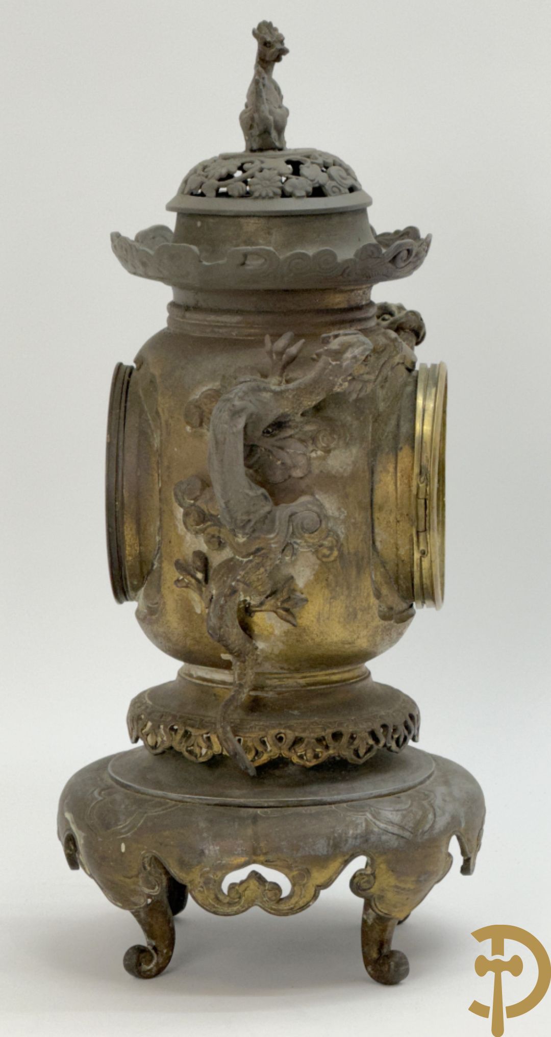 Aziatische pendule in zamak, zijdelings bezet met drakendecor en bovenaan met mythologisch figuur