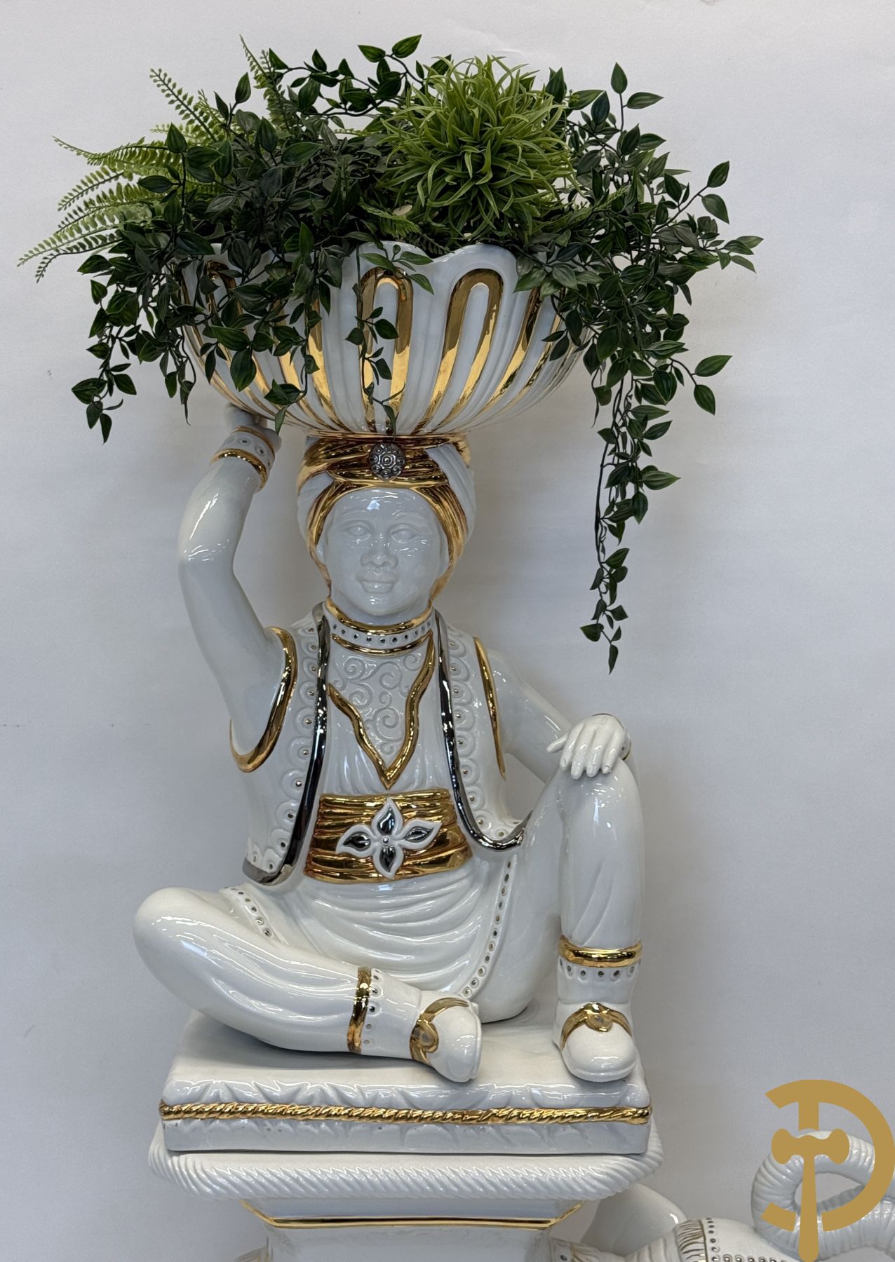 Porseleinen sierbeeld van olifant als staander met daarboven jongeman met bloemencachepot