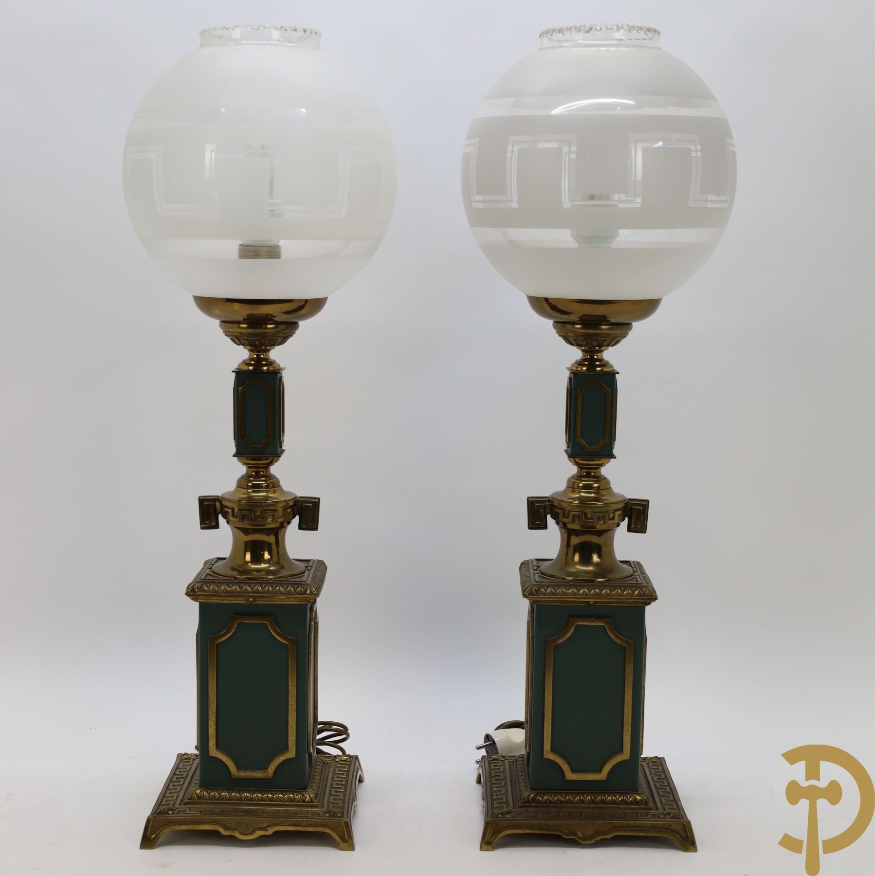 Paar koperen lampadaires met groene fond en bolvormige glazen kappen met meanderend decor
