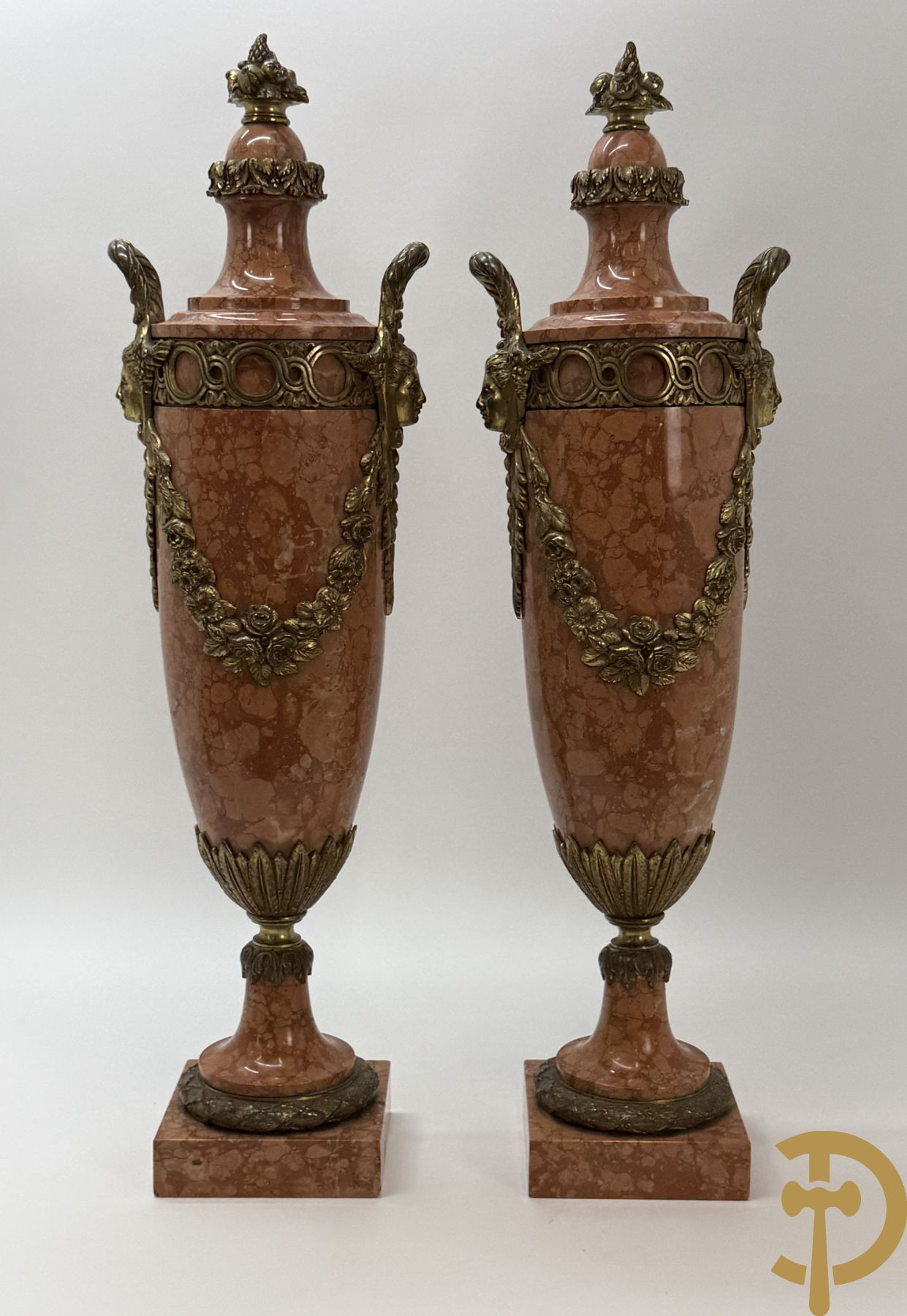 Paar oranje/rode marmeren cassolettes, zijdelings bezet met dameshoofden dragende een guirlande van bloemen - bovenaan met bloementroffee