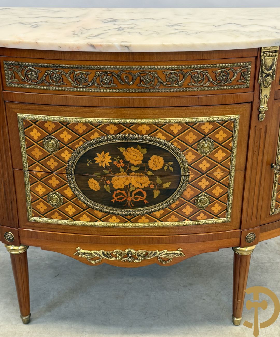 Halve maanvormige drieladencommode met 2 zijdelingse deuren, gemarketteerde bloemenmotieven en bronzen ornamenten, bovenaan bezet met marmeren blad