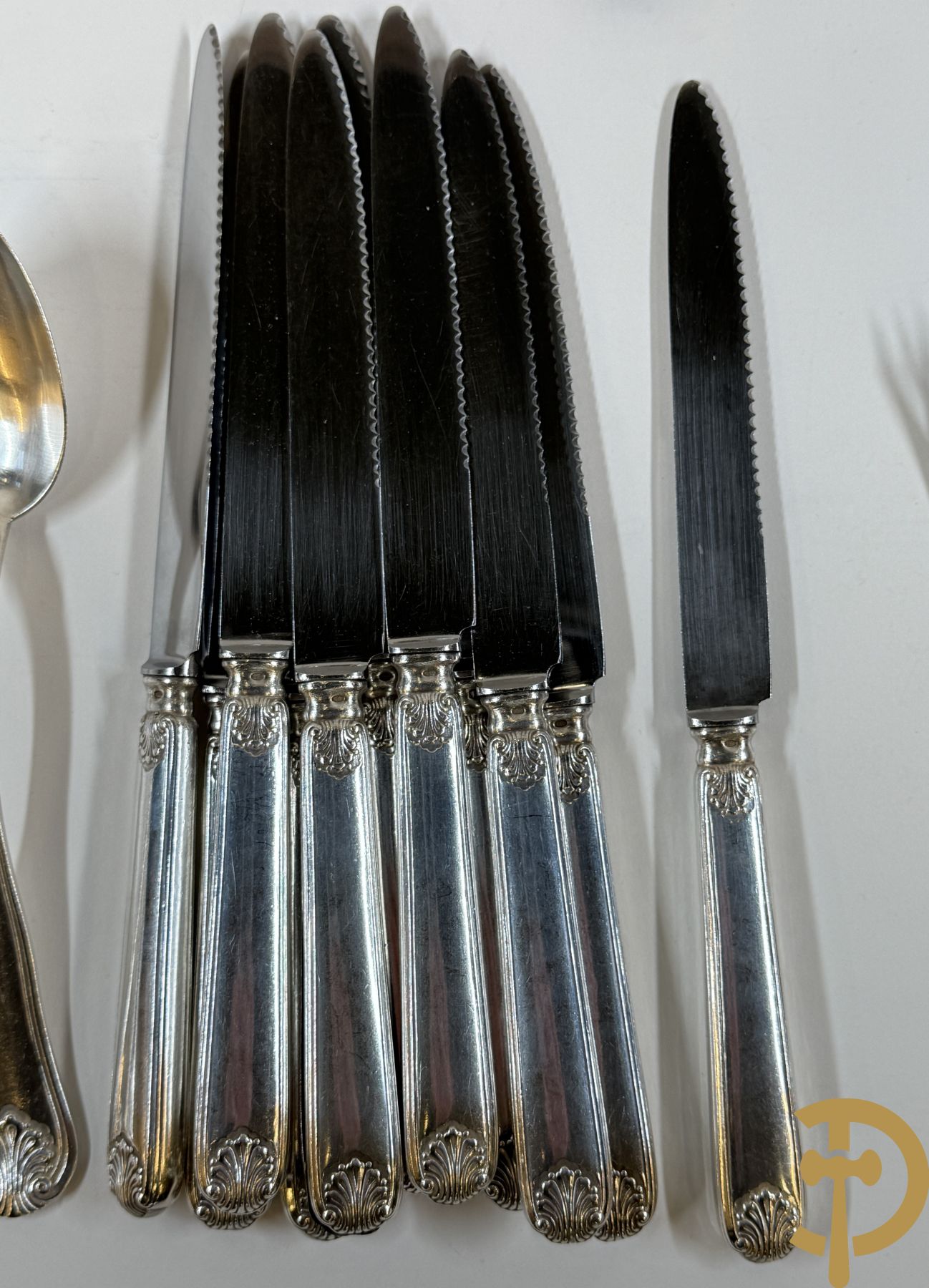 Massief zilveren bestek Wolfers bestaande uit 12 vorken (979 gram), 12 lepels (1028 gram), 11 messen, 12 visvorken (553 gram), 12 vismessen (690 gram), 12 dessertmessen, 10 koffielepels (296 gram), 12 ijslepels (369 gram), 3 botermesjes en scheplepeltje (165 gram), 5  grote stukken (samen 557 gram) waarvan slacouvert, 2 taartscheppen en wildvork + sauslepel met zelfde decor maar Metal Blanc